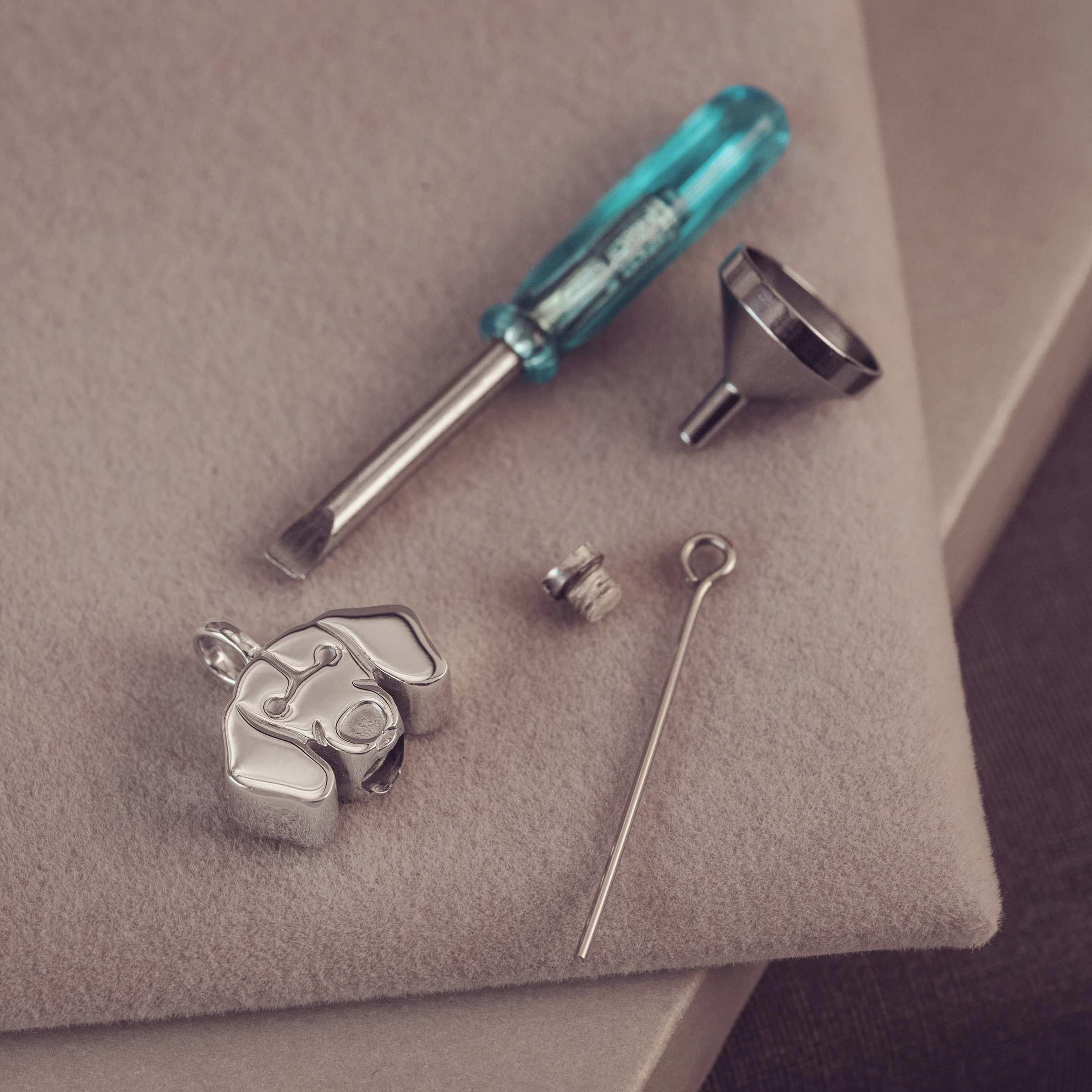Jewelry-making tools including a screwdriver, funnel, and small components on a neutral surface.