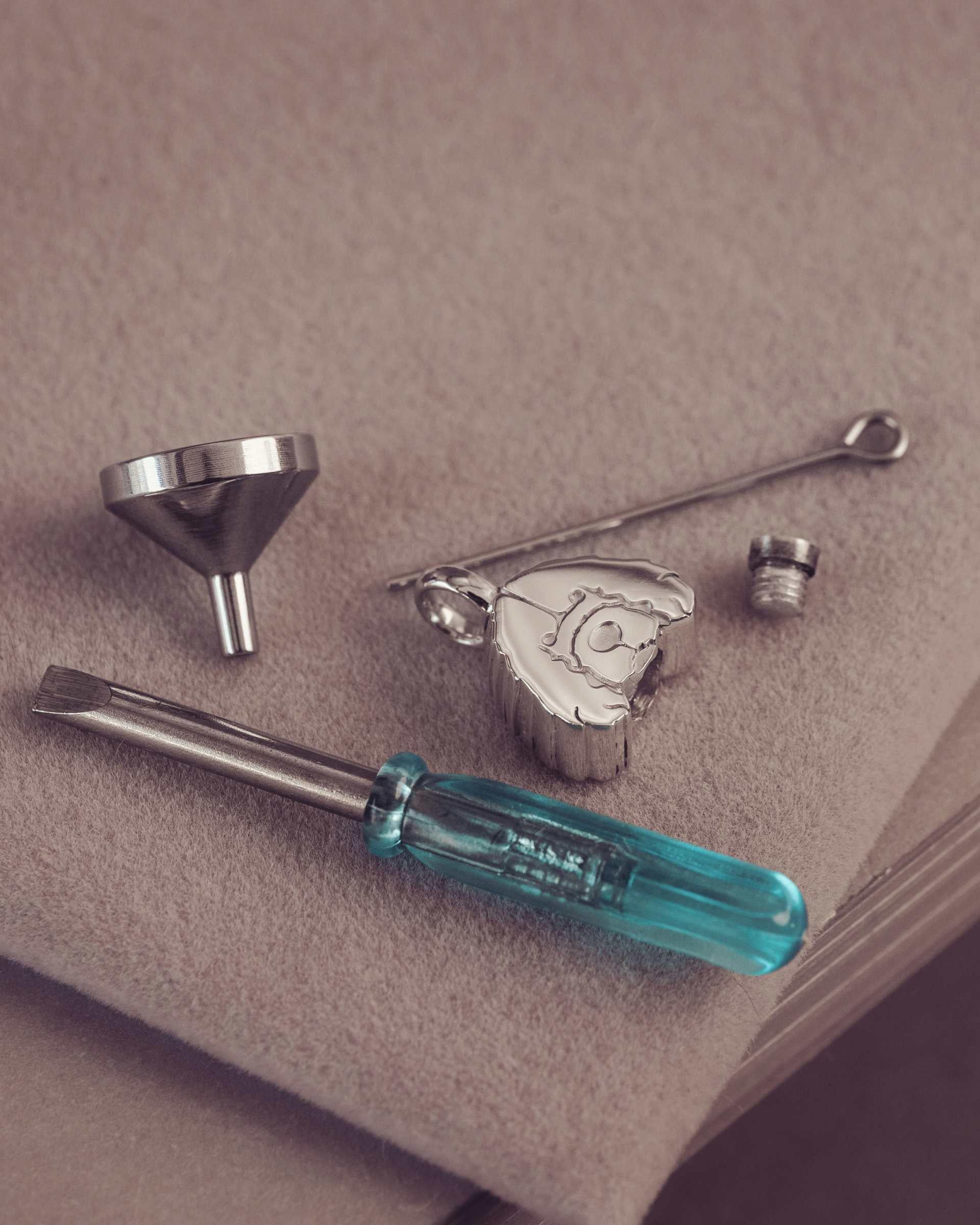 Set of tools including a funnel, screwdriver, and other small items on a beige surface.
