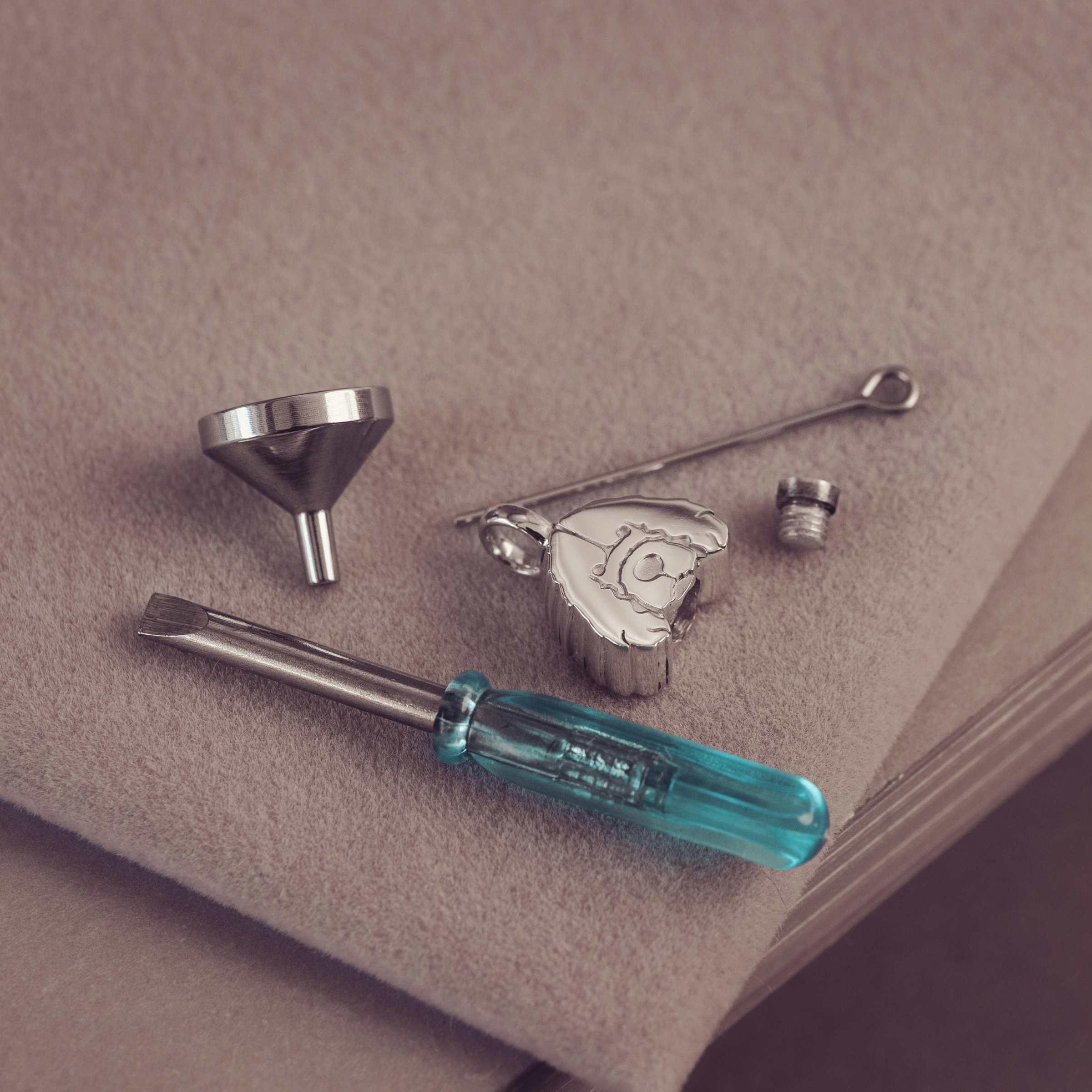 Set of tools including a funnel, screwdriver, and other small items on a beige surface.