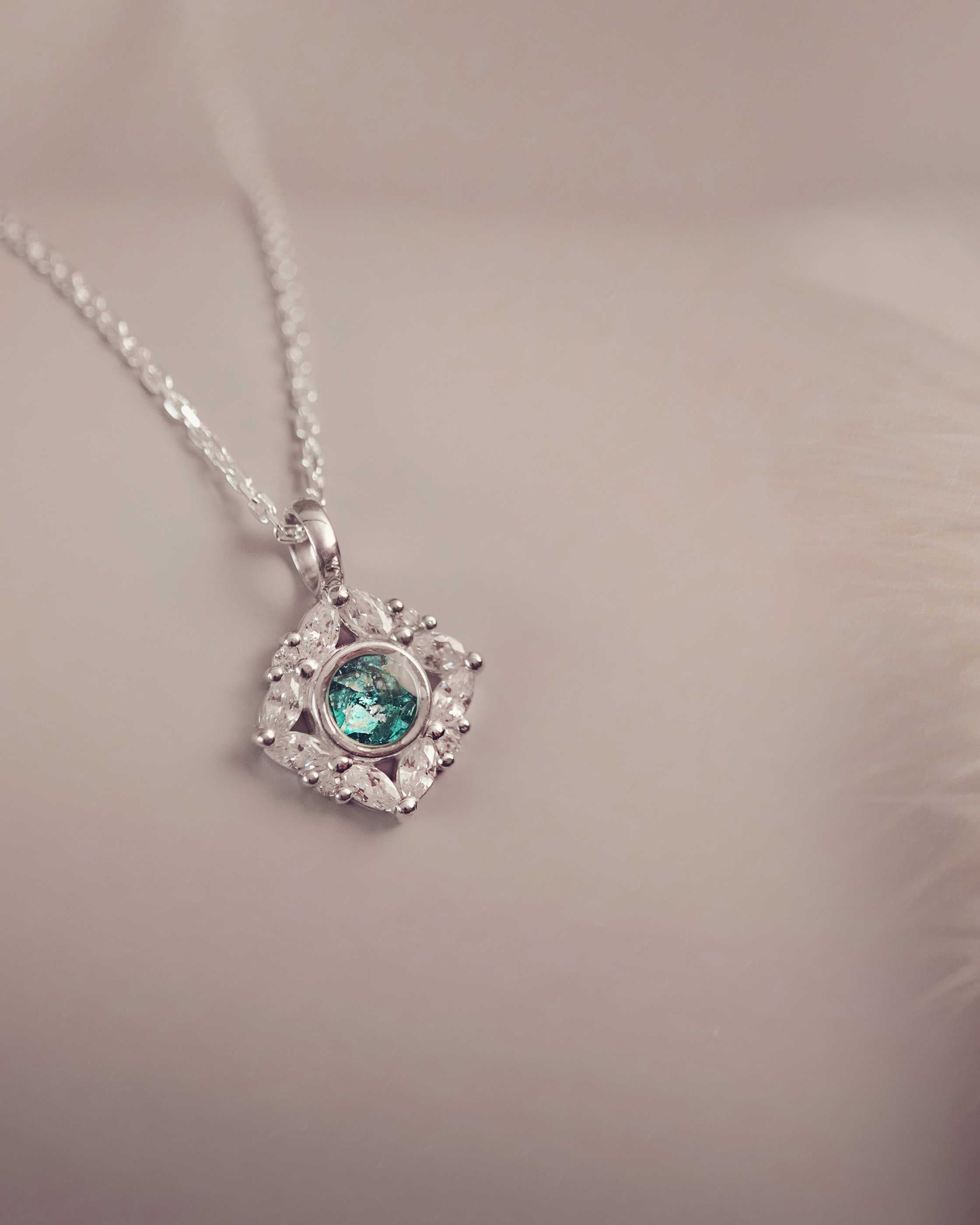 Silver heart-shaped pendant with a green gemstone on a soft background