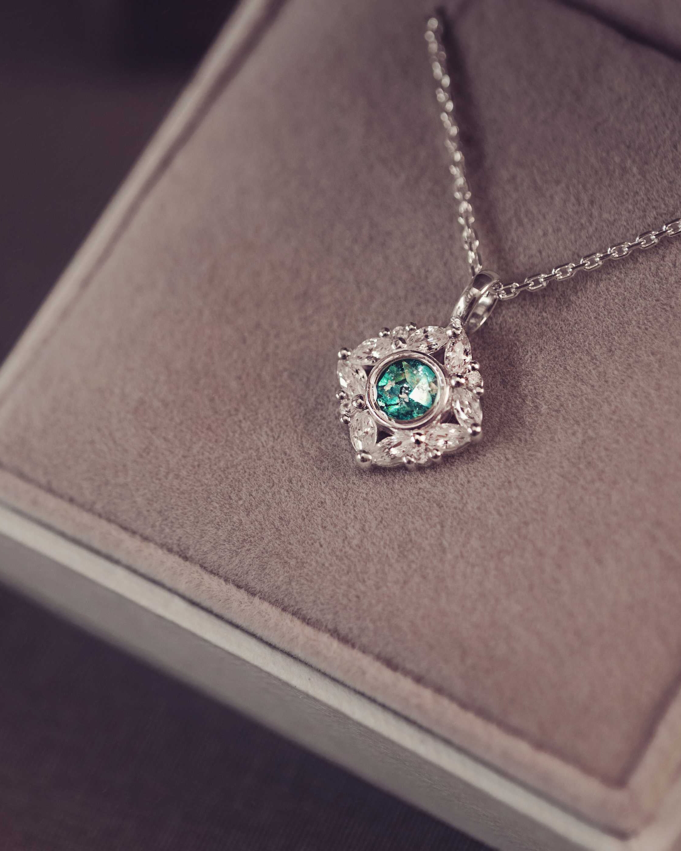 Silver necklace with a green gemstone pendant on a soft surface