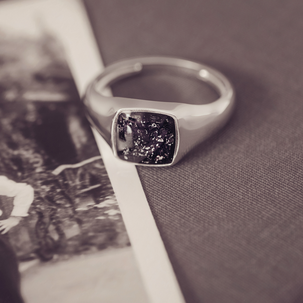Silver ring with a dark stone on a textured surface