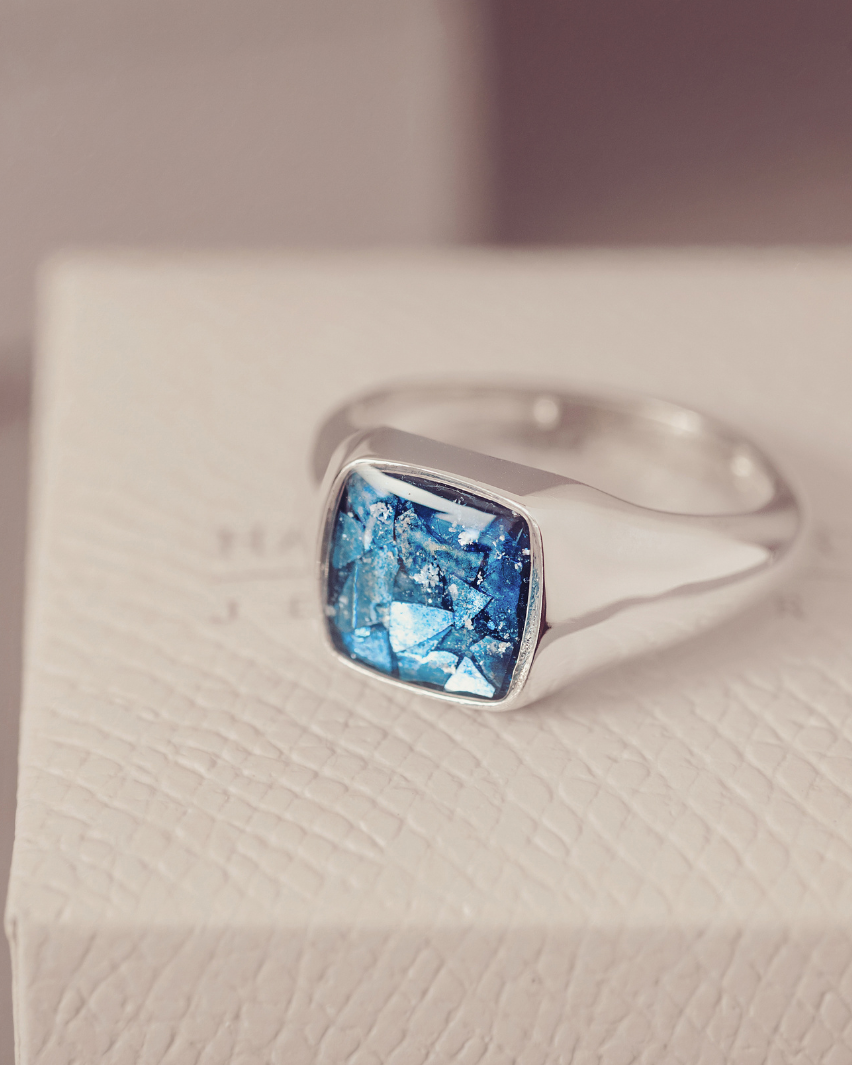 Silver ring with a blue gemstone on a textured surface