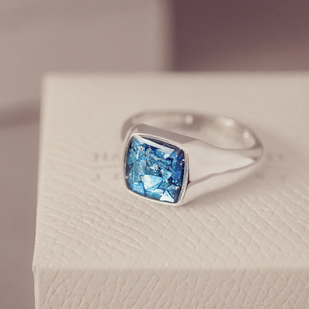 Silver ring with a blue gemstone on a textured surface