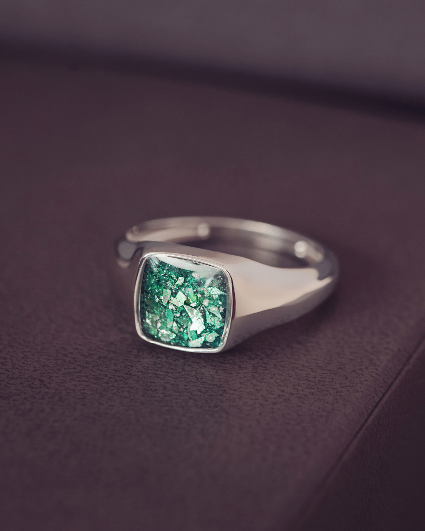 Silver ring with a green gemstone on a dark purple surface