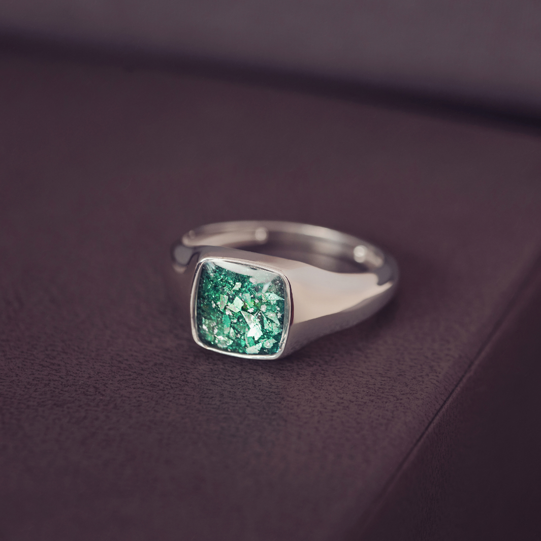 Silver ring with a green gemstone on a dark purple surface