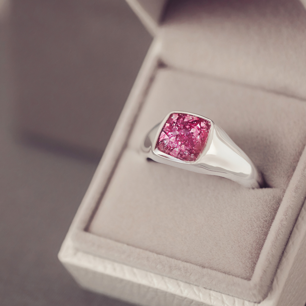 Silver ring with a pink gemstone in a jewelry box