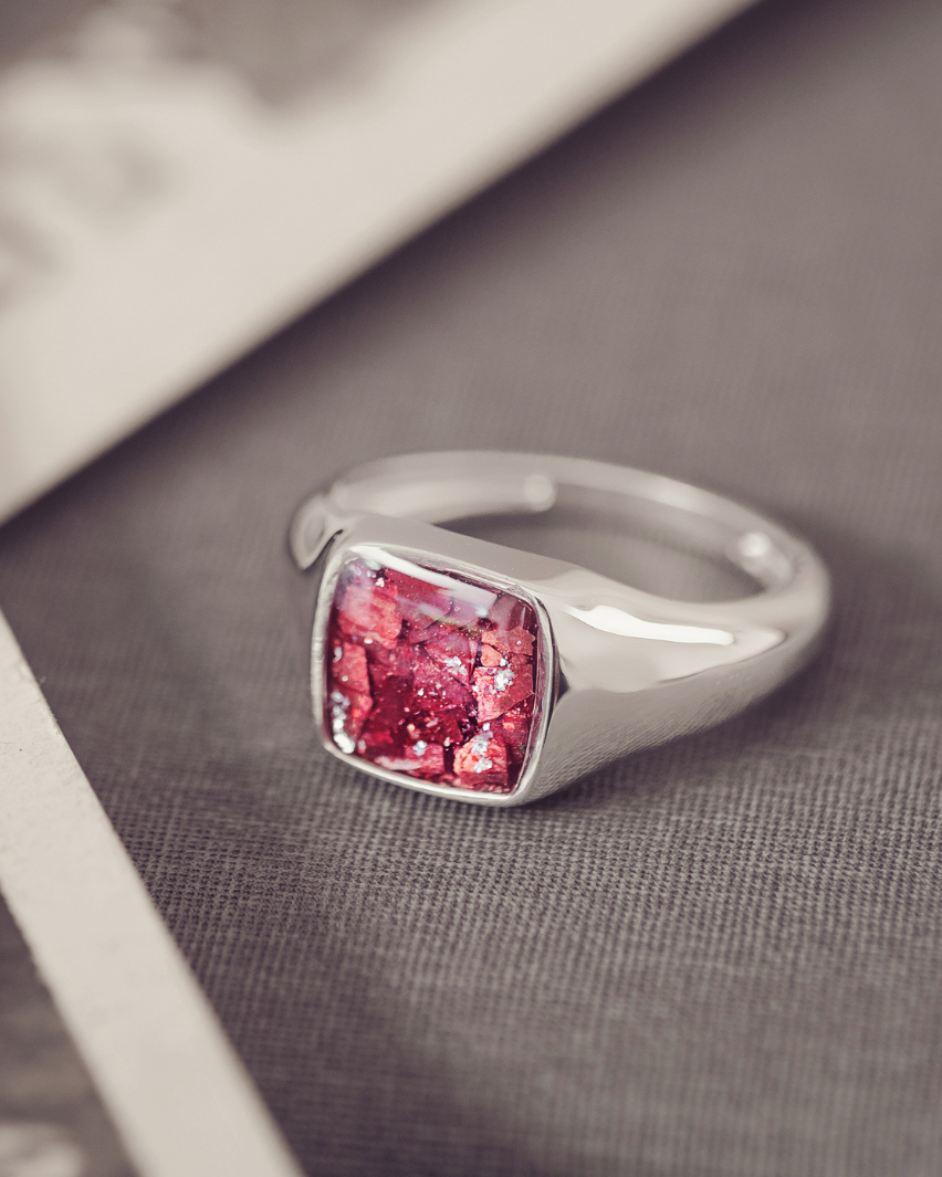 Silver ring with a red gemstone on a textured surface