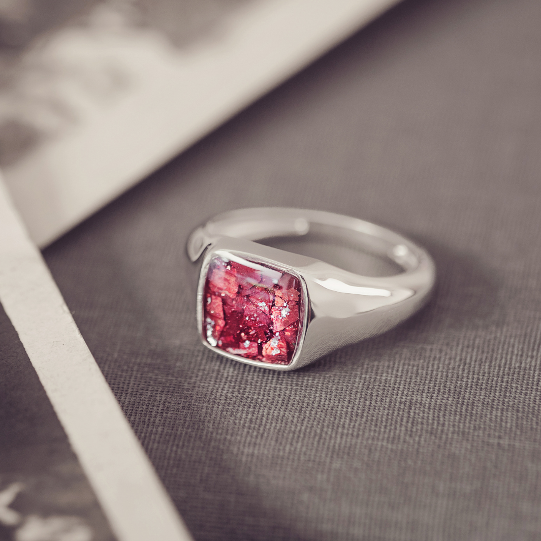 Silver ring with a red gemstone on a textured surface