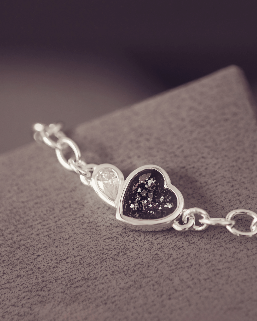 Silver bracelet with a heart-shaped charm on a textured surface