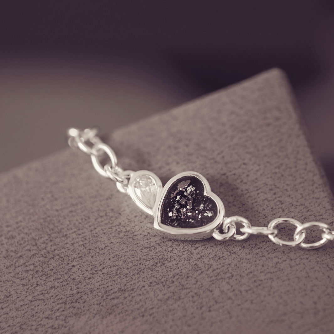 Silver bracelet with a heart-shaped charm on a textured surface