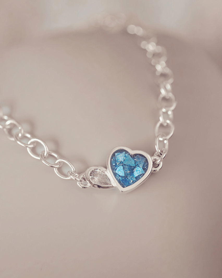 Silver bracelet with a heart-shaped blue gemstone on a soft background