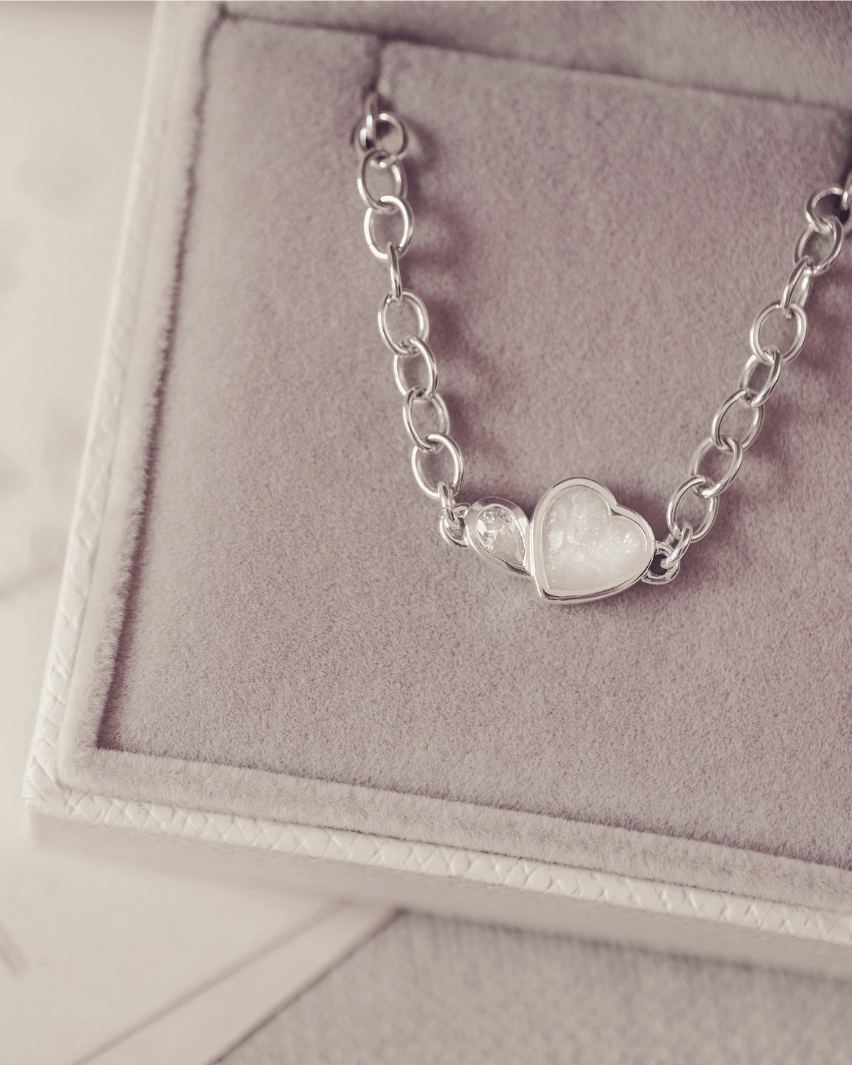 Silver bracelet with a heart-shaped charm on a gray jewelry box