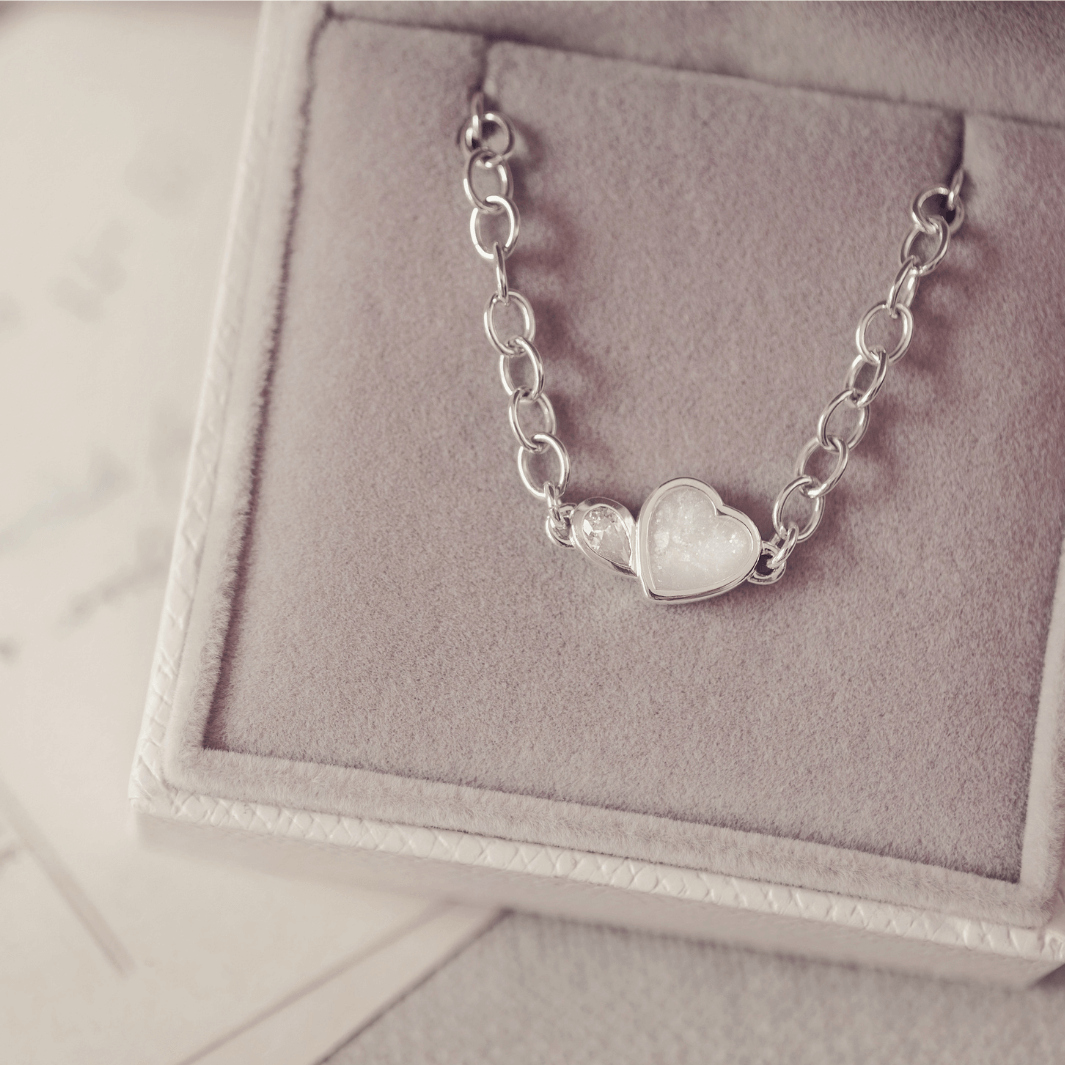 Silver bracelet with a heart-shaped charm on a gray jewelry box