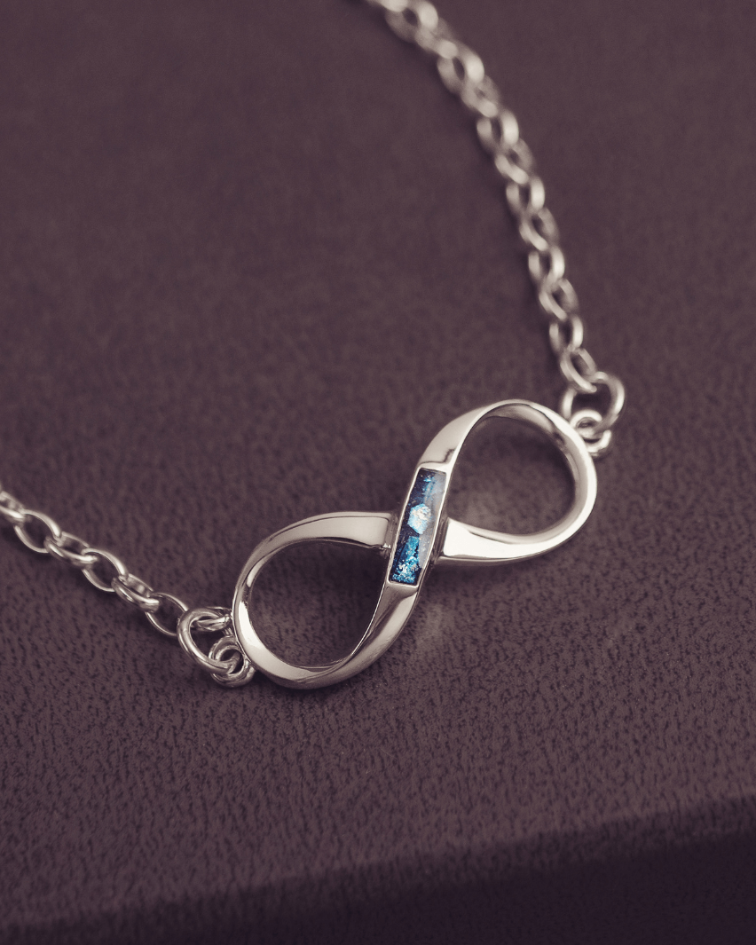 Silver infinity necklace with a blue gemstone on a dark purple background