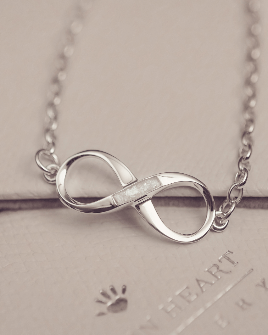 Silver infinity necklace on a light gray background