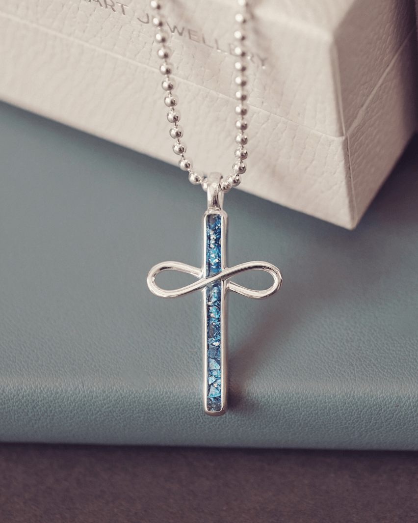 Silver cross necklace with blue stones on a light gray surface