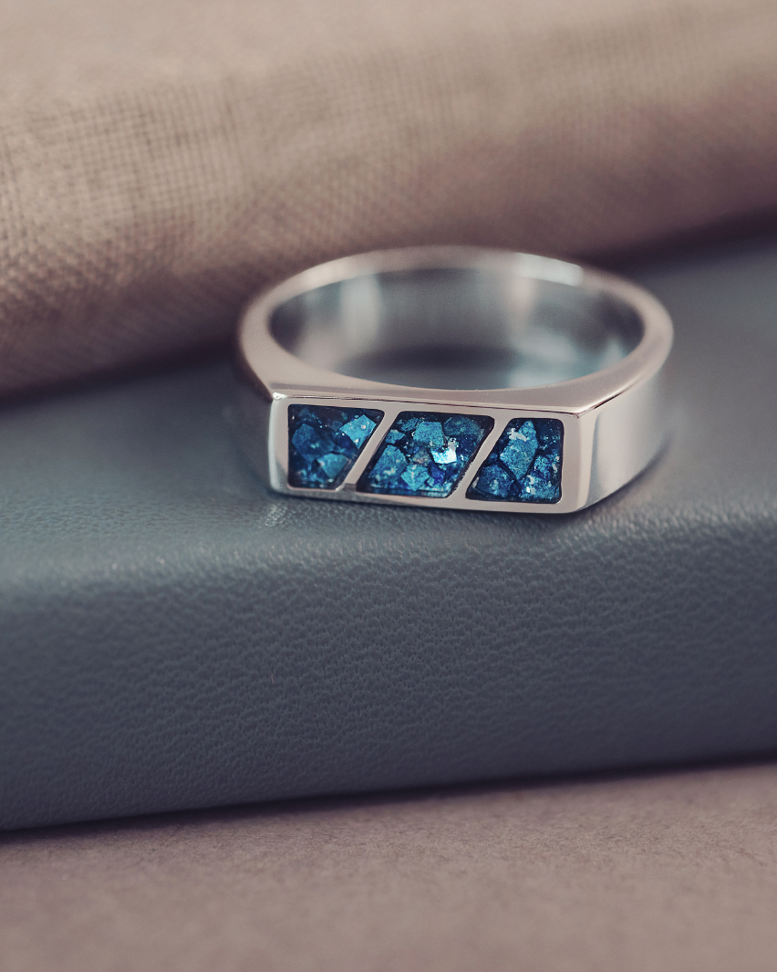 Silver ring with blue gemstones on a textured surface