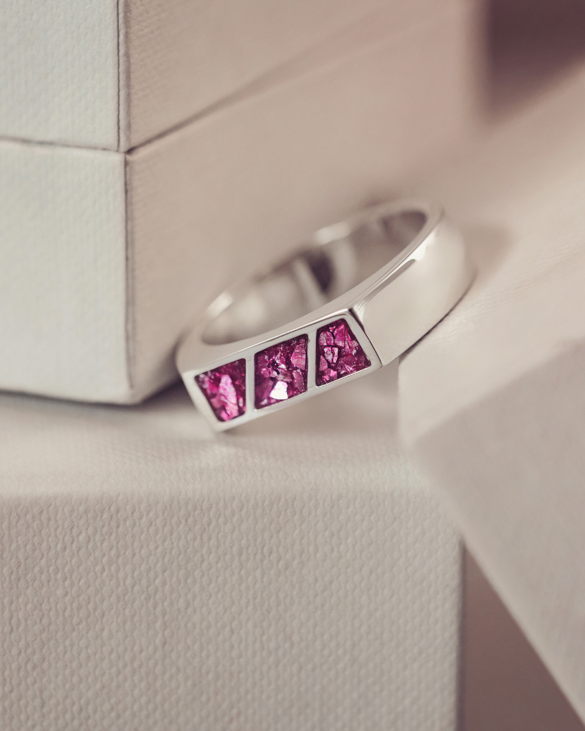 Silver ring with pink gemstones on a textured surface