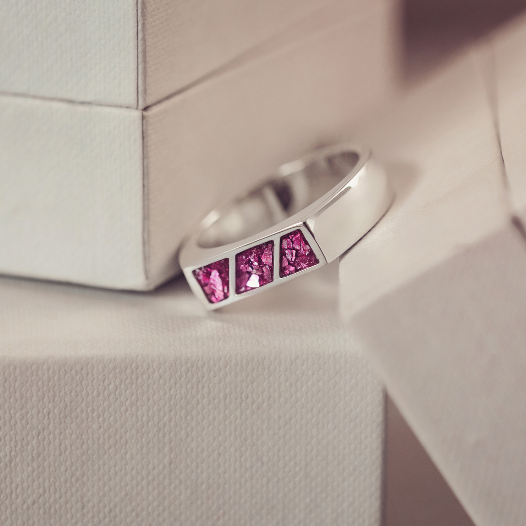 Silver ring with pink gemstones on a textured surface
