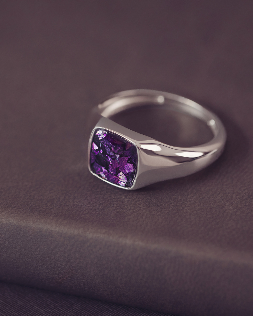 Silver ring with a purple gemstone on a dark fabric background