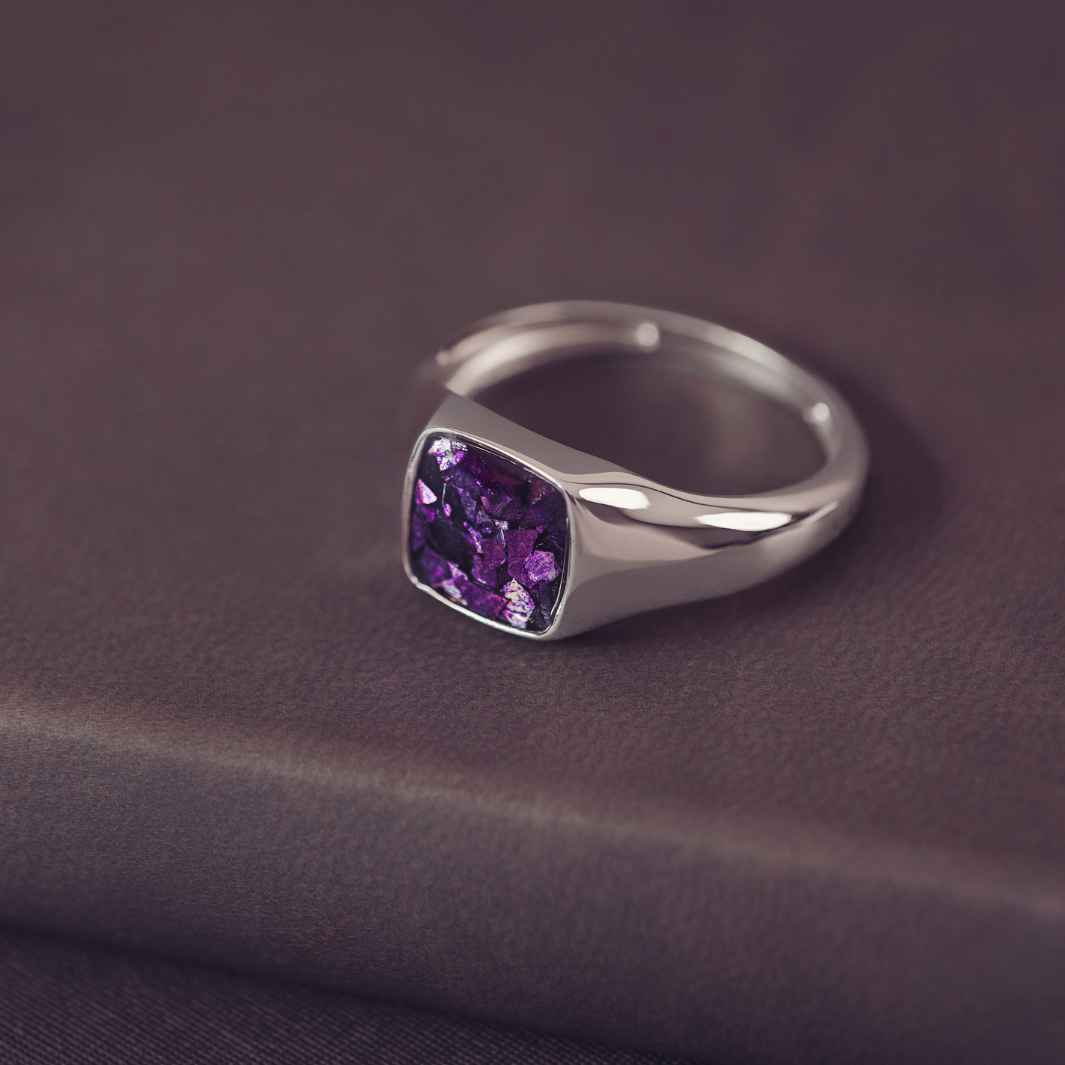 Silver ring with a purple gemstone on a dark fabric background