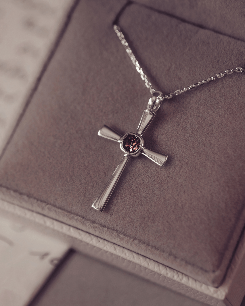 silver cross necklace with a section of resin and brown crystals, holding memorial ashes