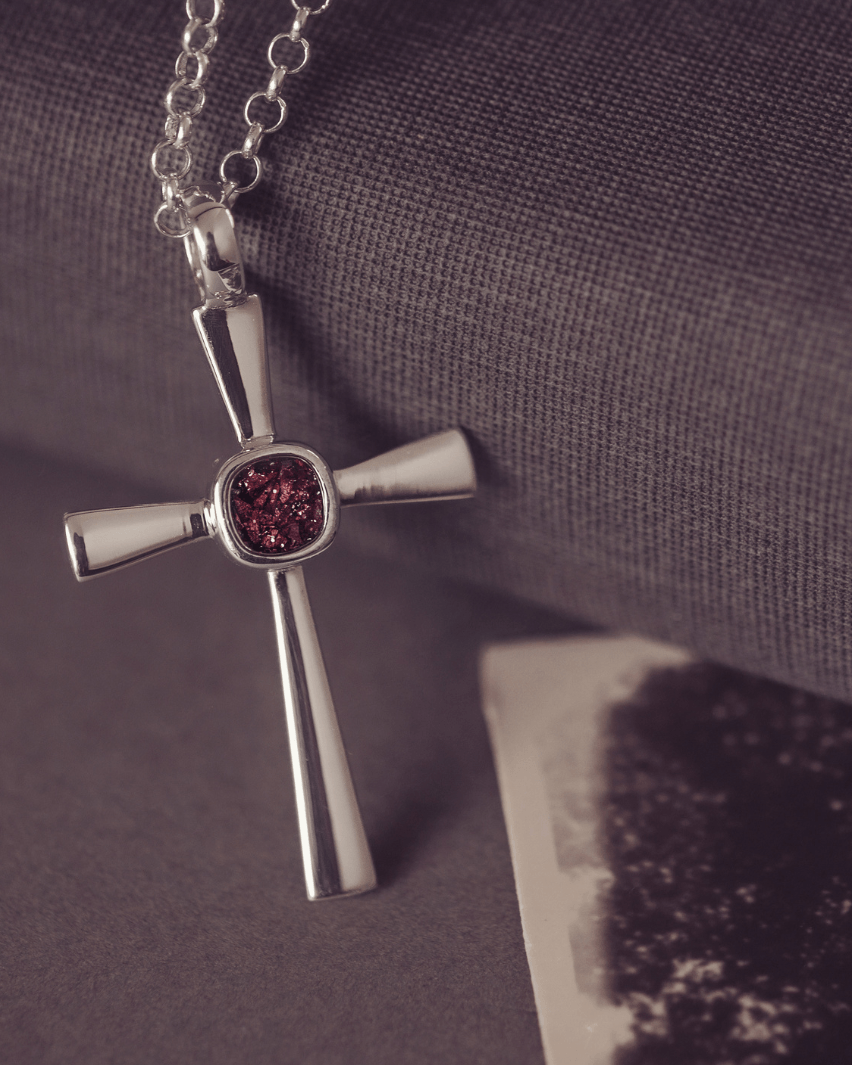 silver cross necklace with a section of resin and brown crystals, holding memorial ashes