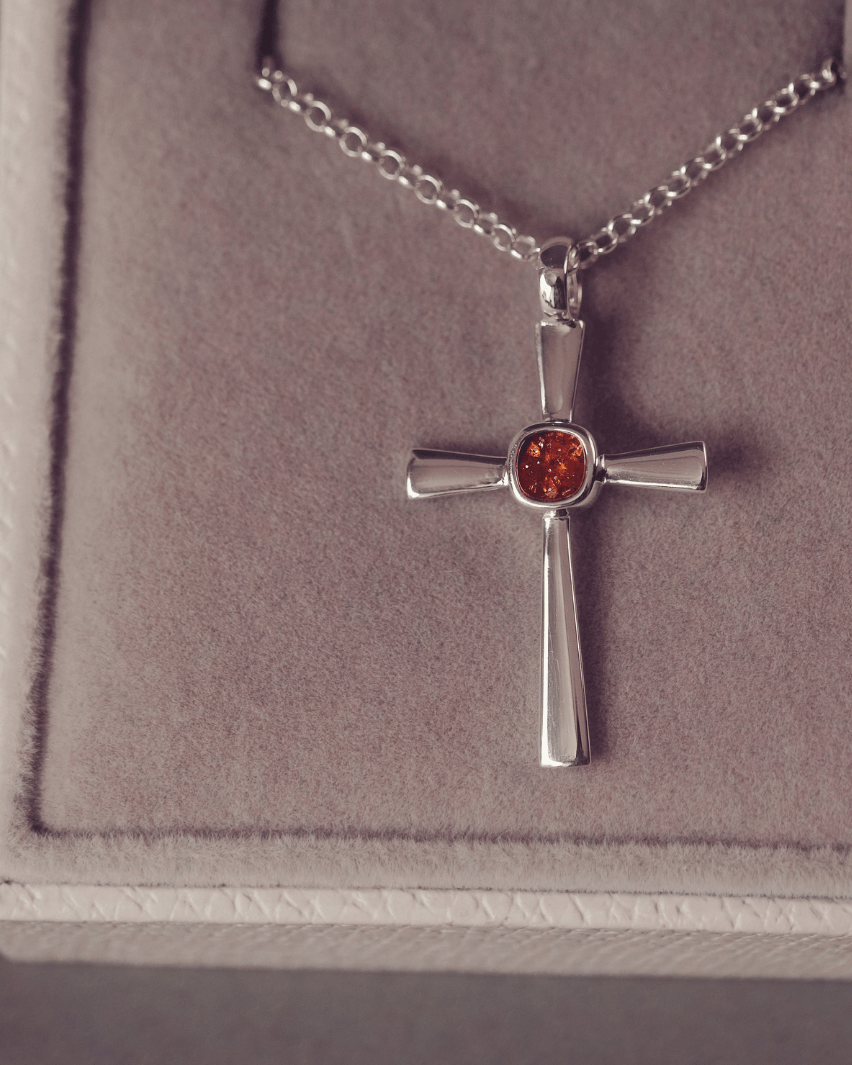 silver cross necklace with a section of resin and orange crystals, holding memorial ashes
