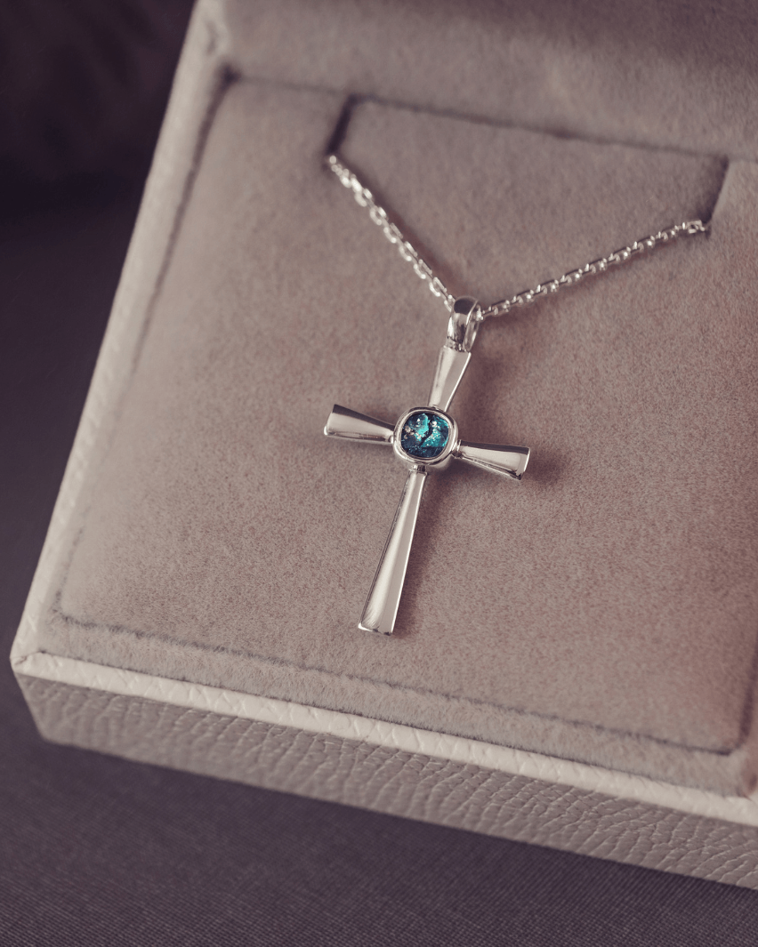silver cross necklace with a section of resin and turquoise crystals, holding memorial ashes