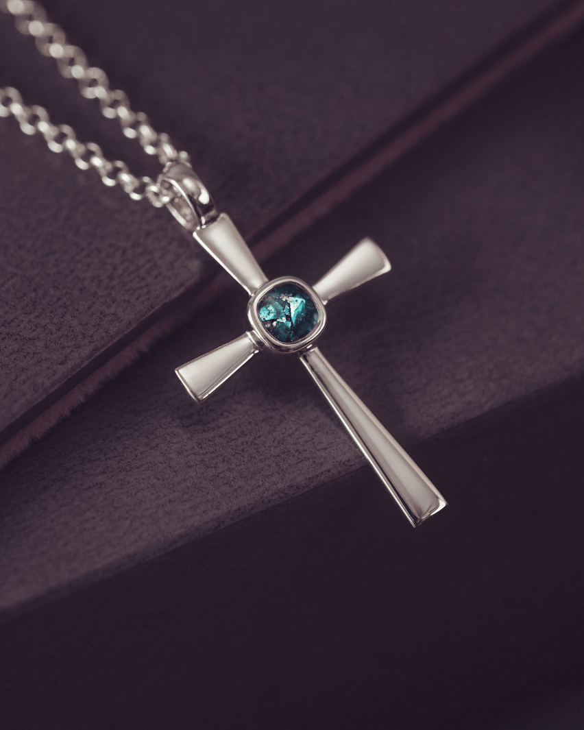 silver cross necklace with a section of resin and turquoise crystals, holding memorial ashes