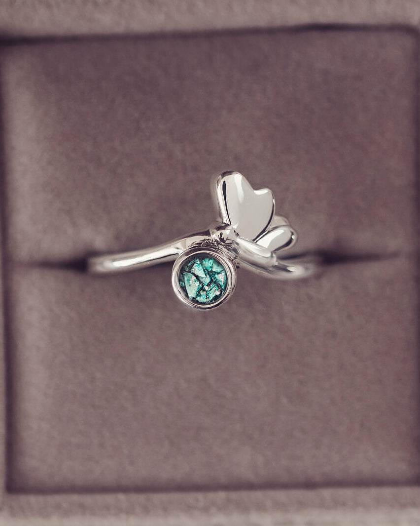 Silver butterfly ring, with green crystals and cremation ashes. In a grey jewellery box.