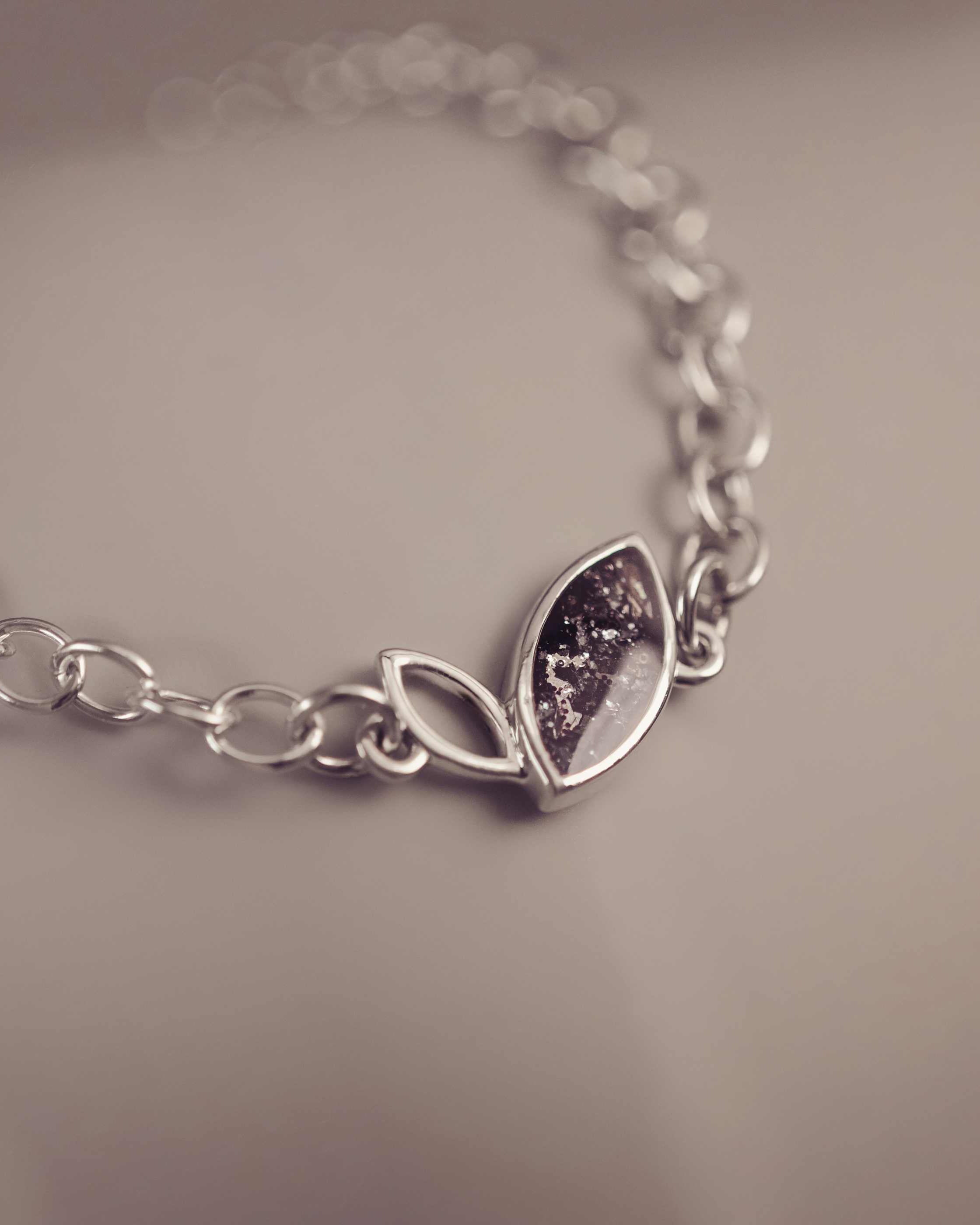 Silver bracelet with a leaf-shaped charm on a neutral background