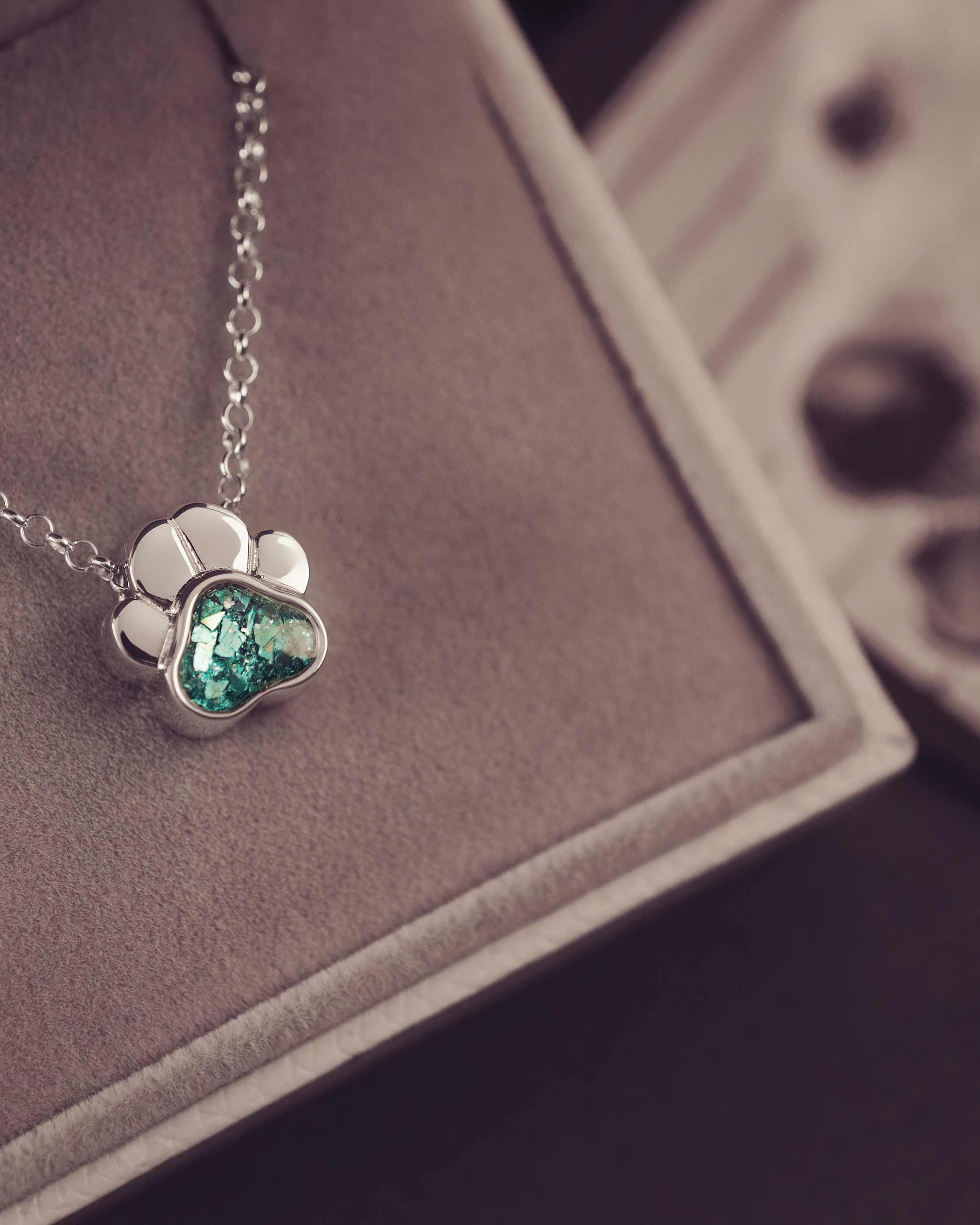 Silver necklace with a heart-shaped green gemstone pendant on a brown surface.