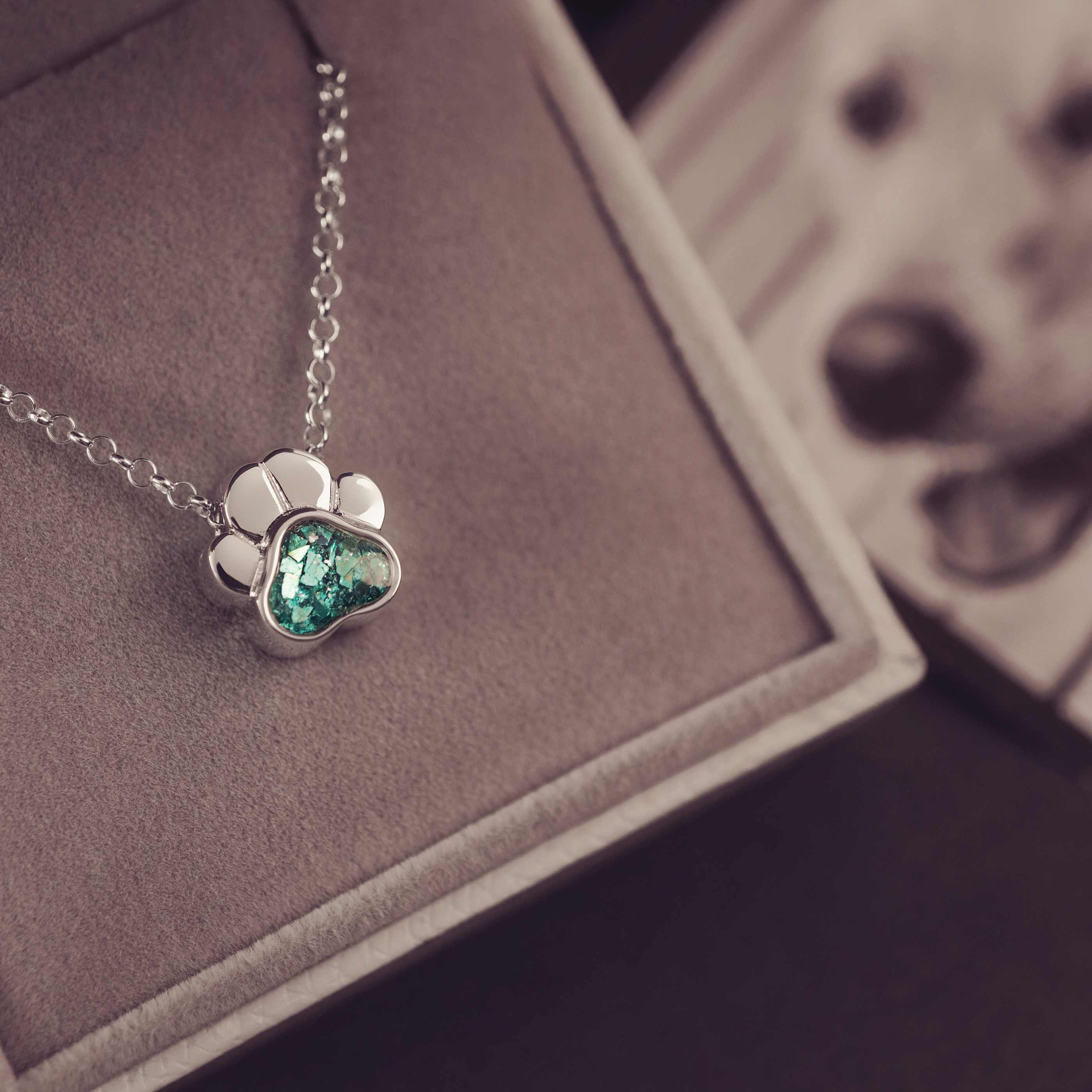 Silver necklace with a heart-shaped green gemstone pendant on a brown surface.