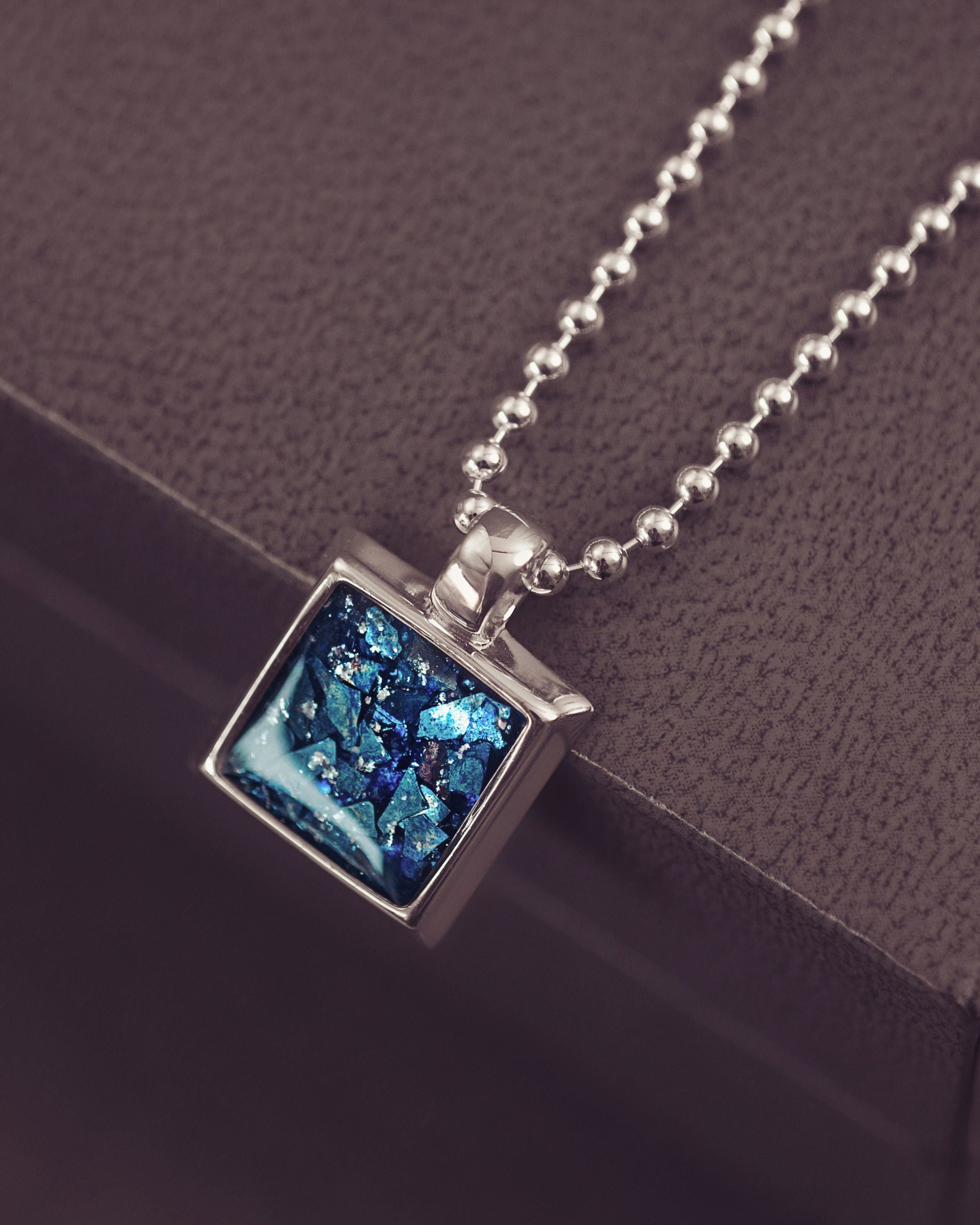 Necklace with a blue pendant on a dark surface