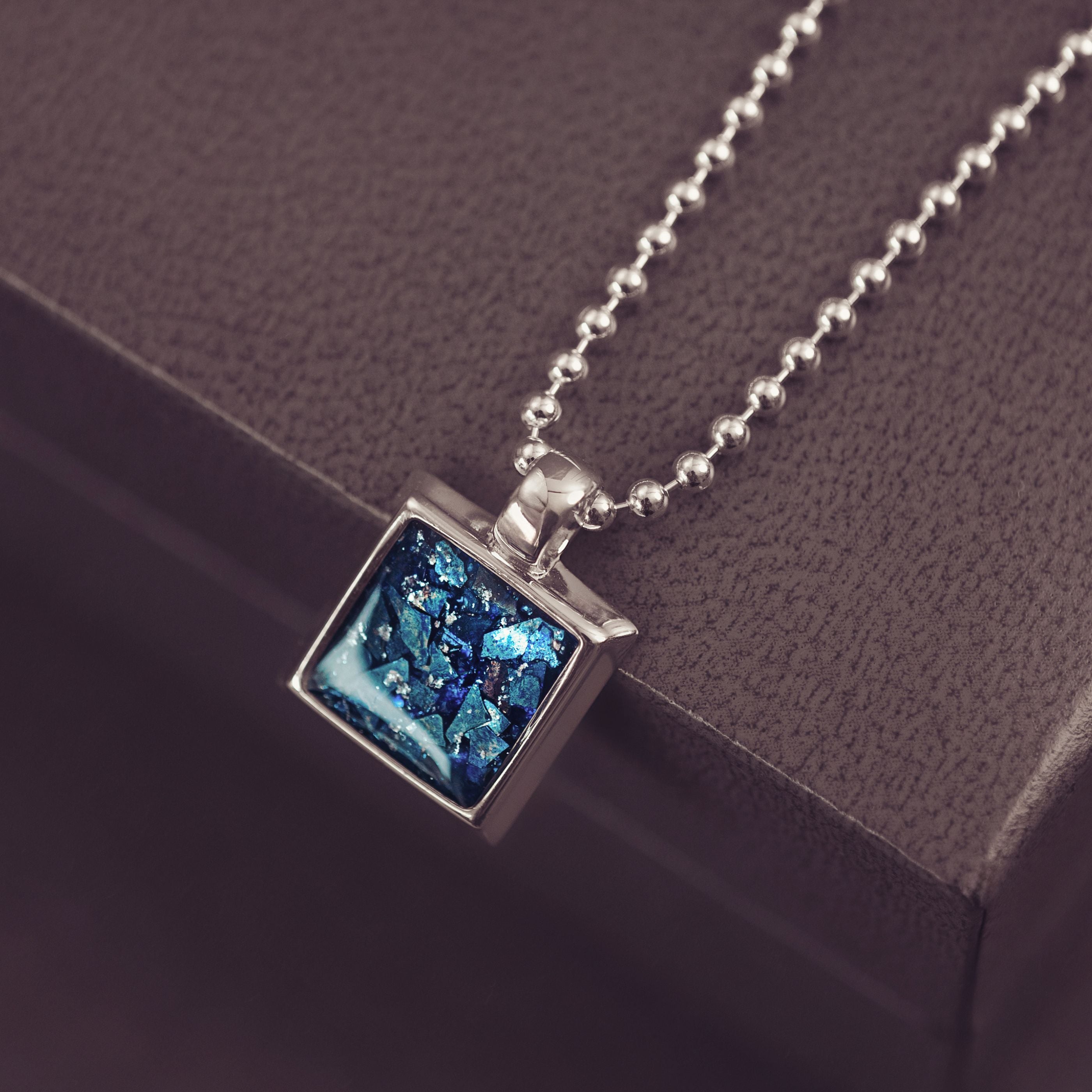 Necklace with a blue pendant on a dark surface