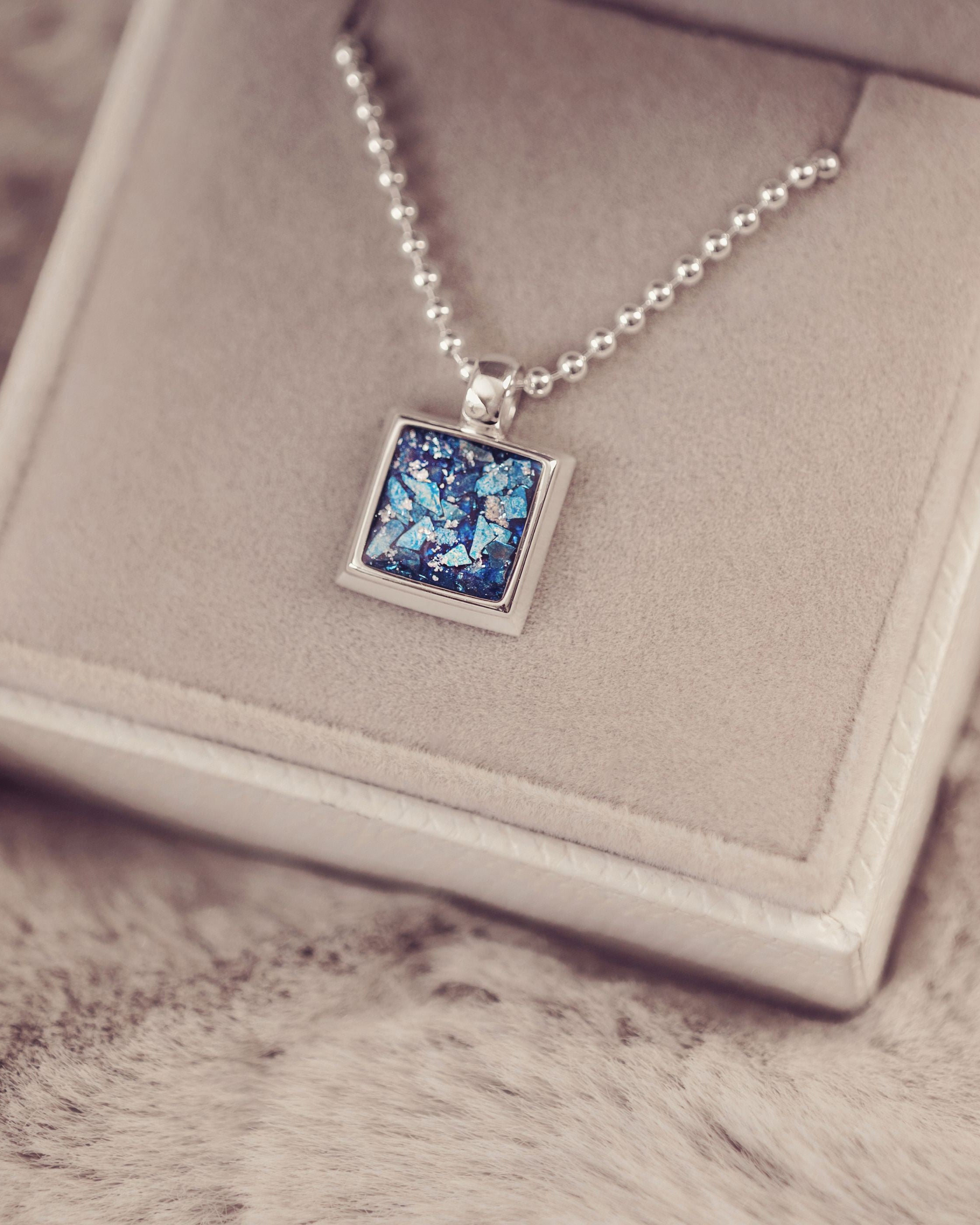 Necklace with a blue pendant on a textured surface