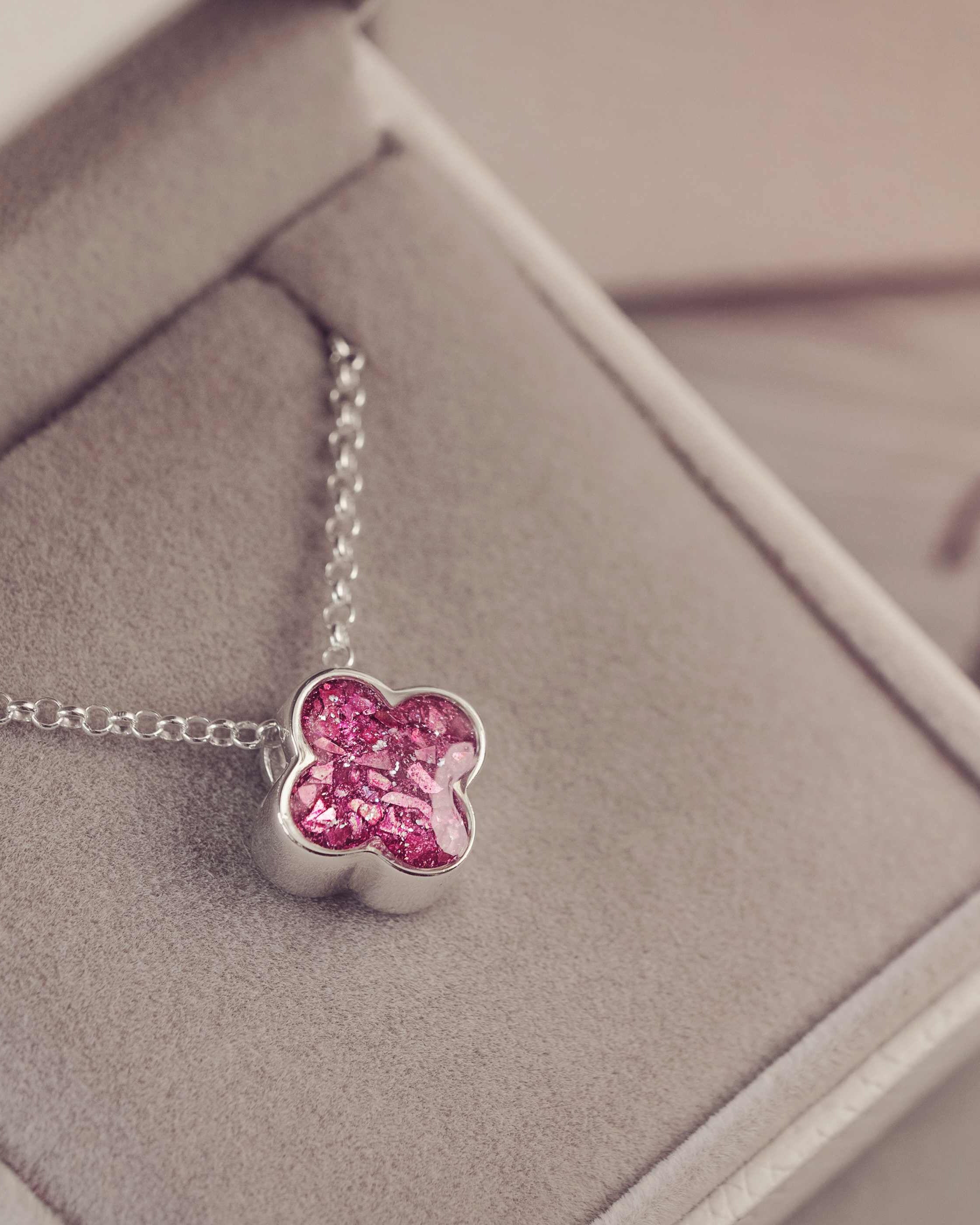 Pink clover-shaped pendant on a silver chain in a jewelry box