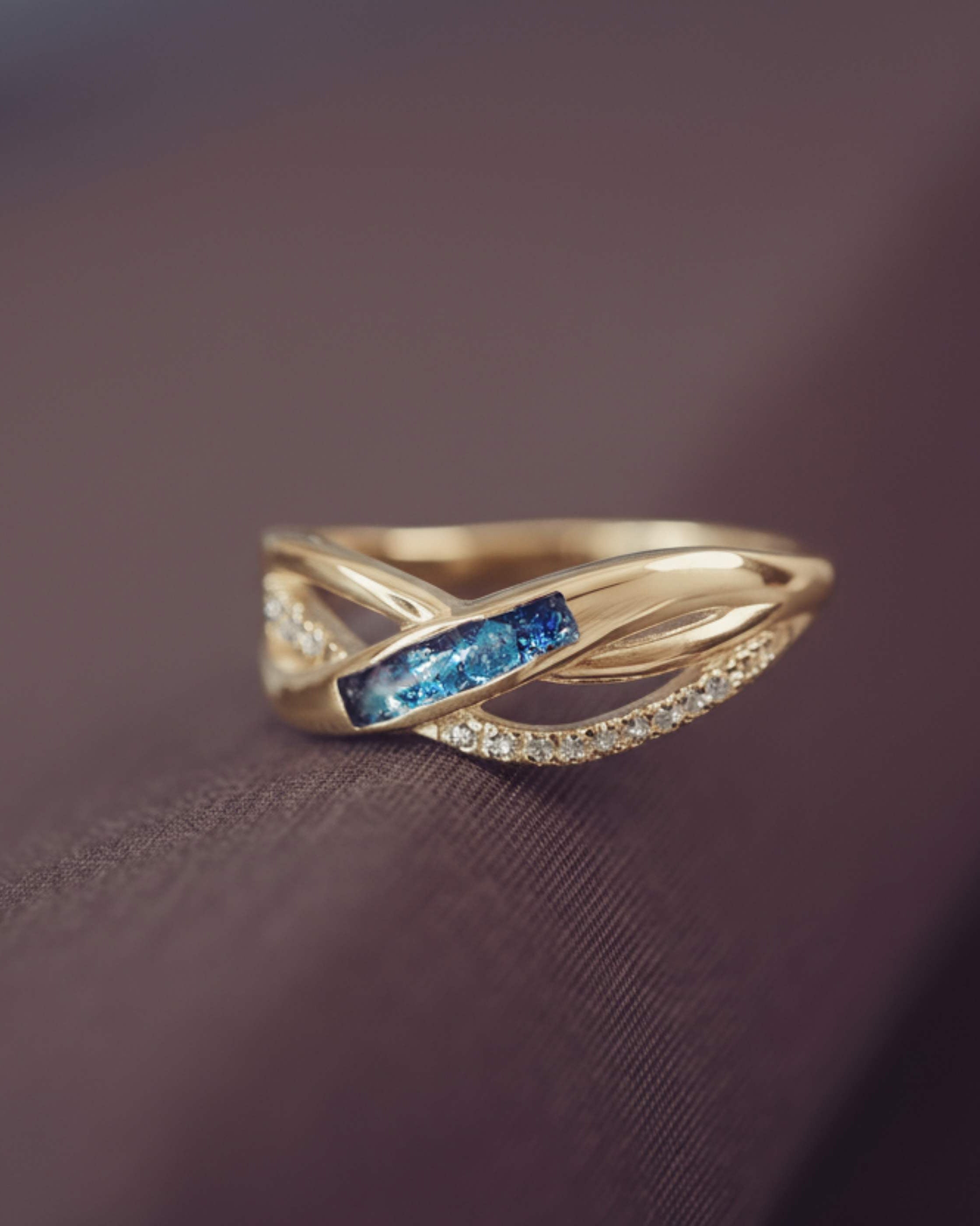 Gold ring with blue gemstone on a dark fabric background