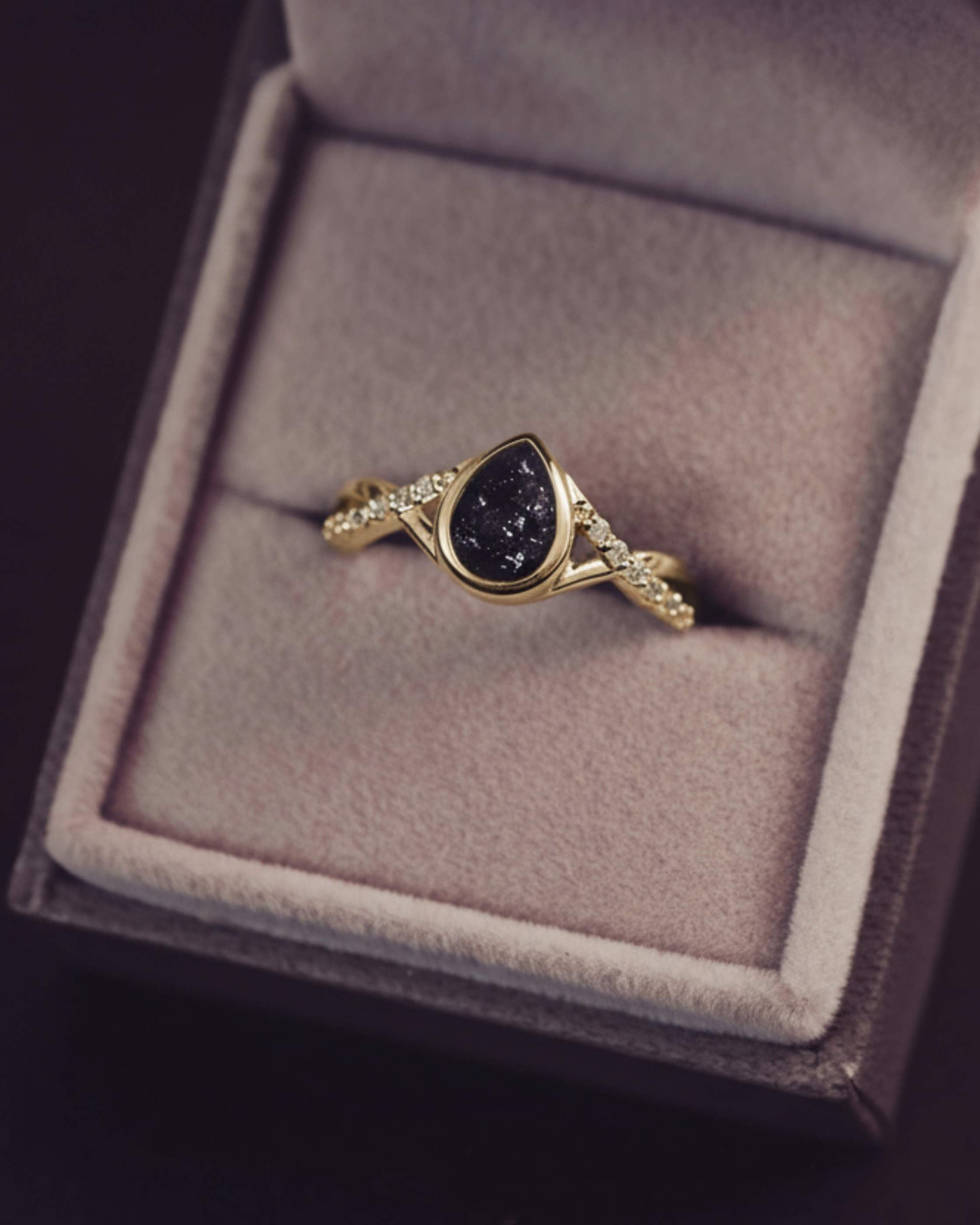 Gold ring with a dark gemstone in a jewelry box