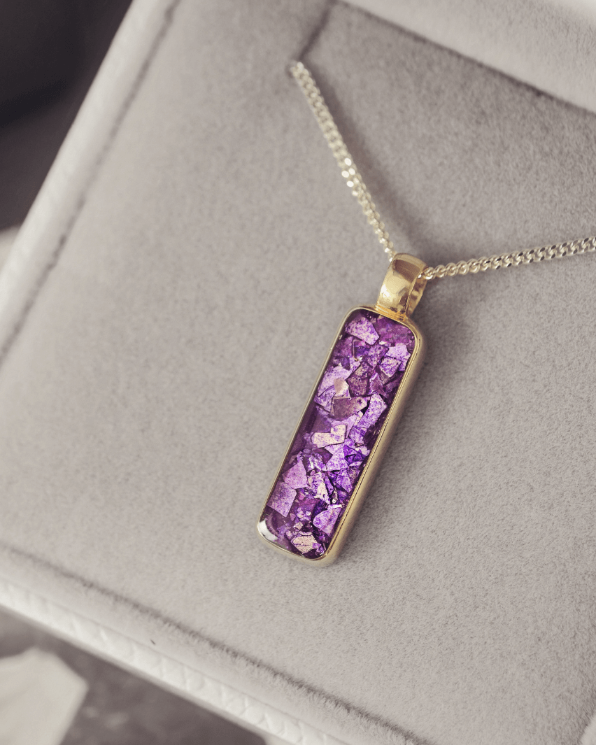 9ct yellow gold necklace with a purple setting on a gray surface