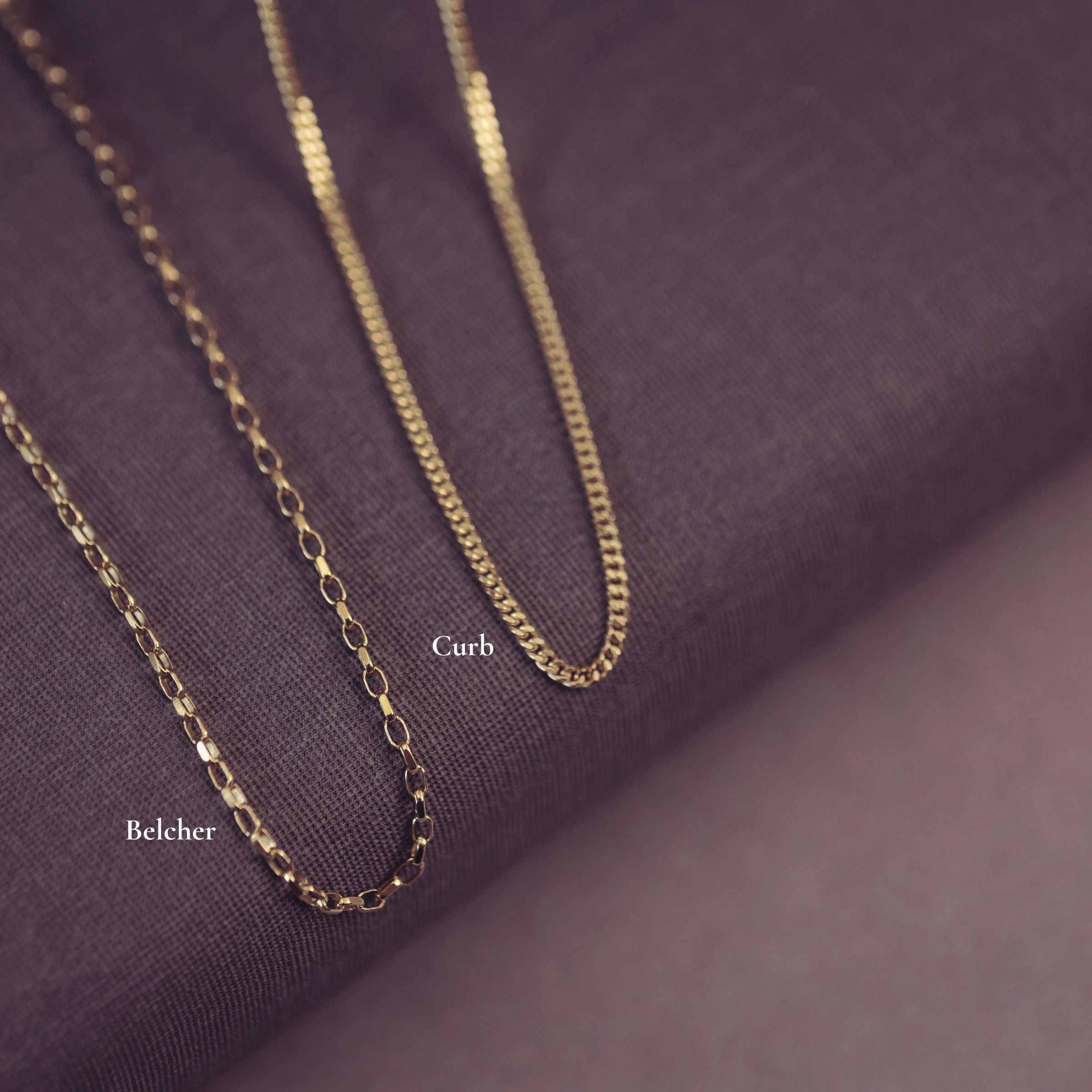 Gold chain necklace on a purple fabric background with 'Curb' and 'Belcher' labels.