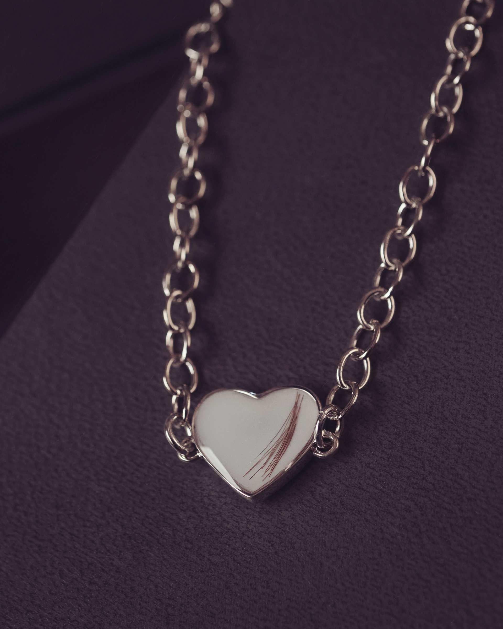 Silver heart-shaped bracelet on a dark purple background