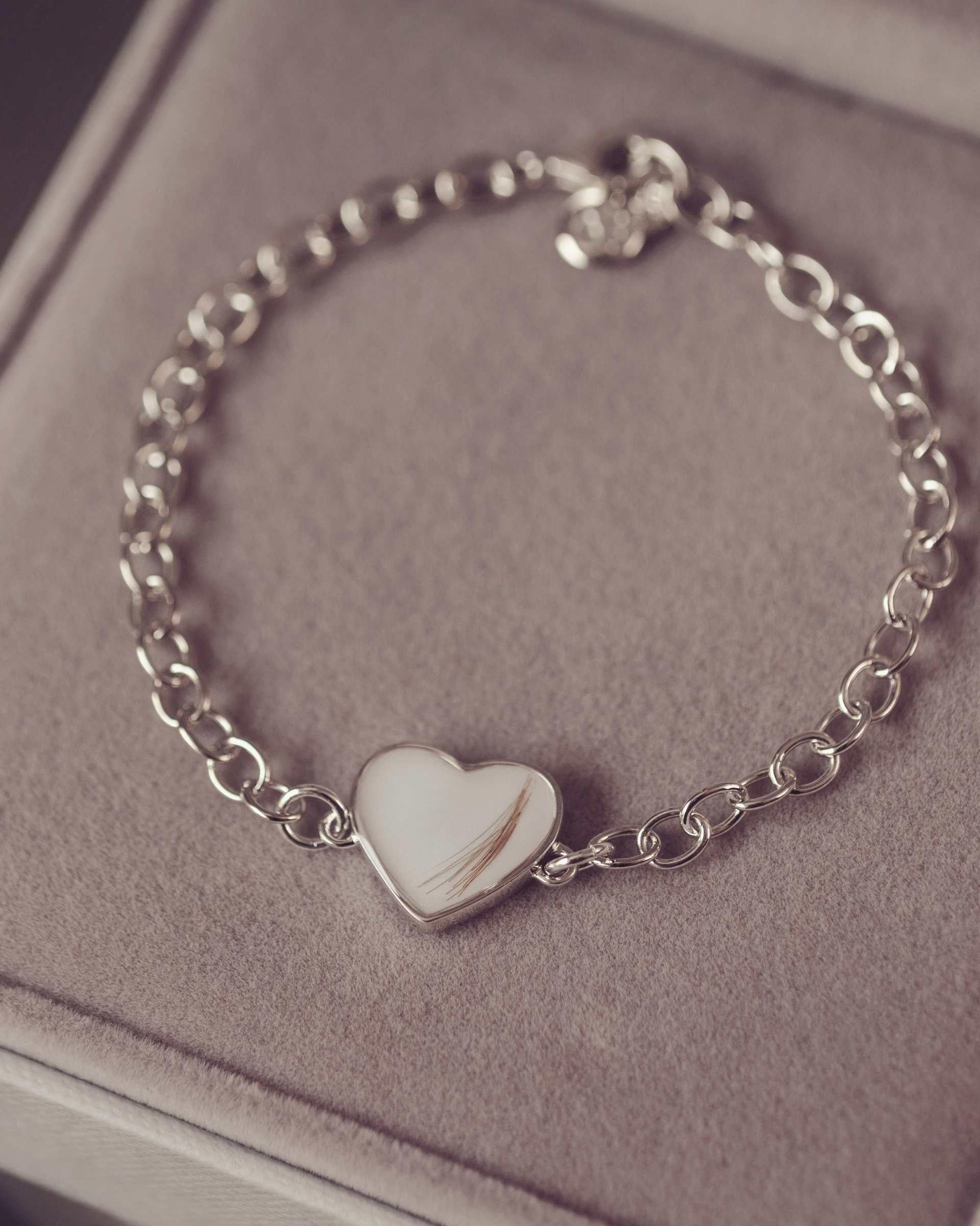 Silver bracelet with a heart-shaped charm on a soft surface