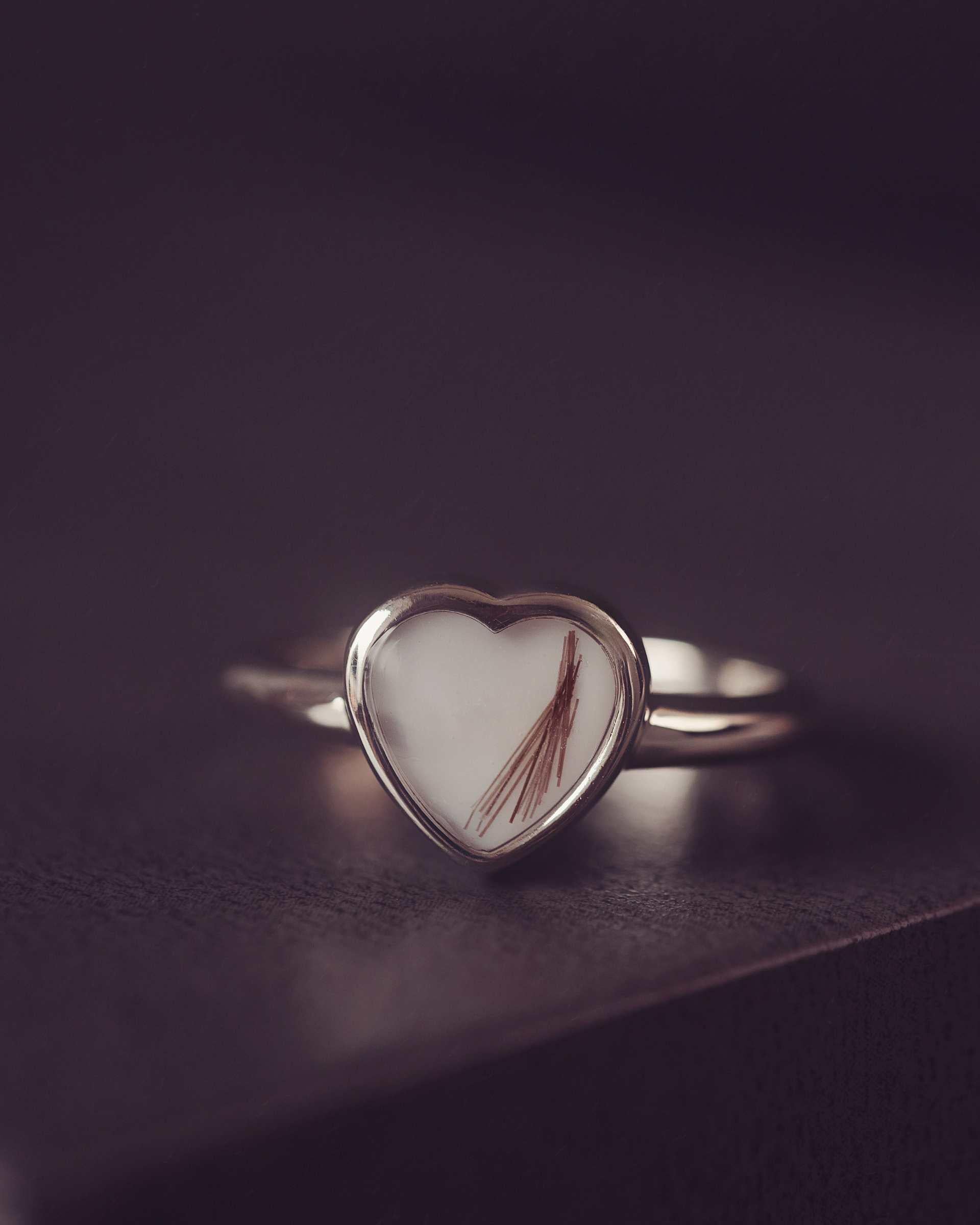 Heart-shaped ring with a hair on a dark surface
