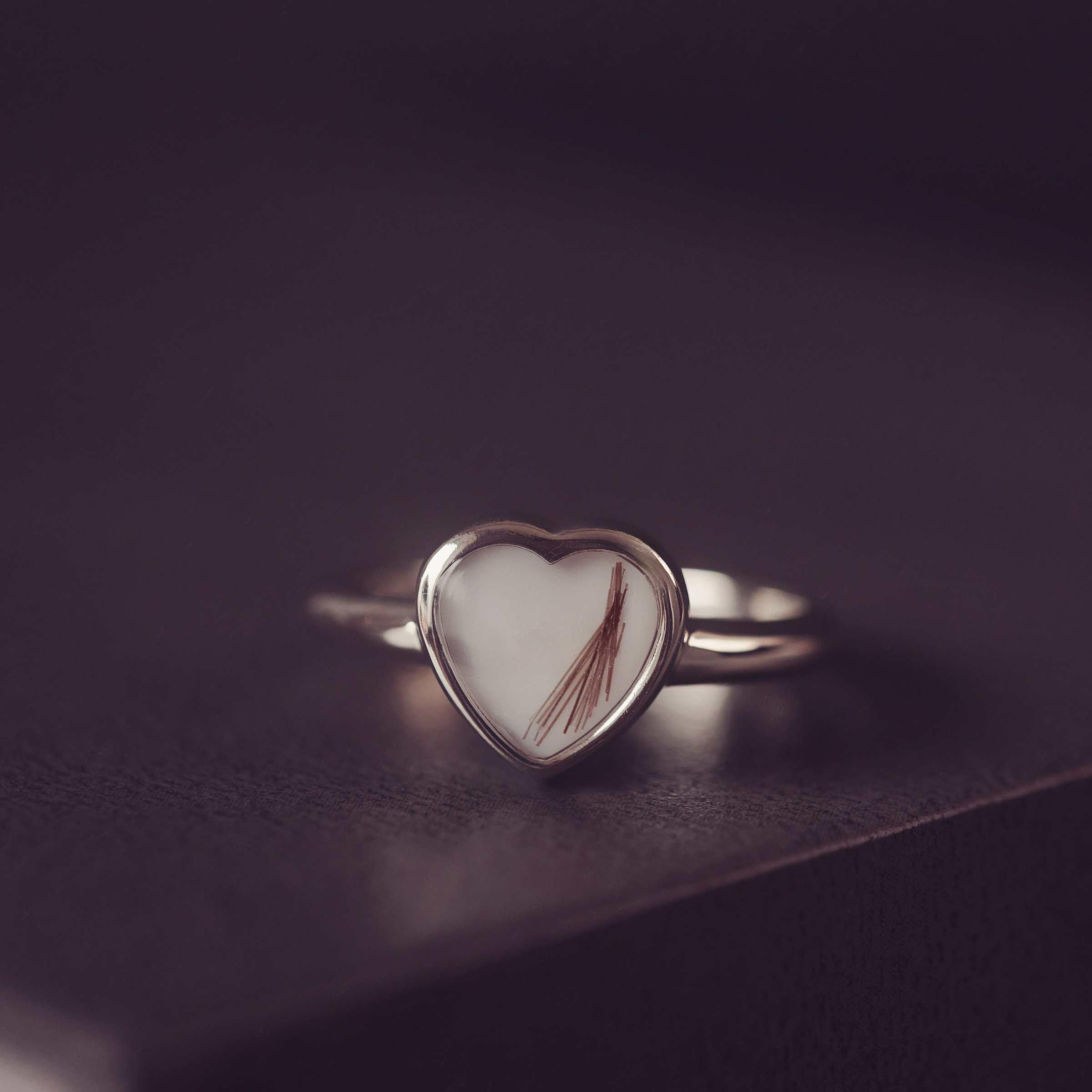 Heart-shaped ring with a hair on a dark surface