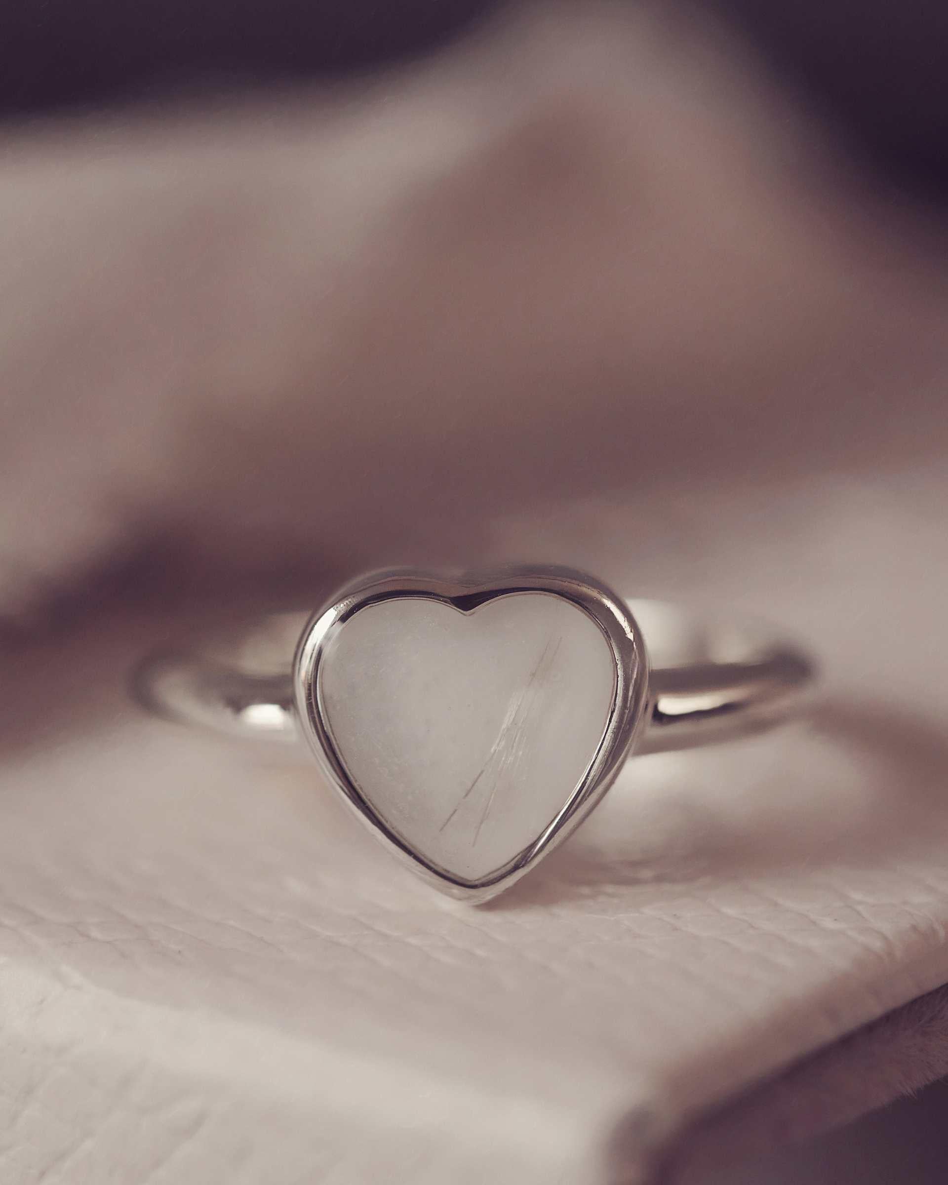 Heart-shaped silver ring on a textured surface