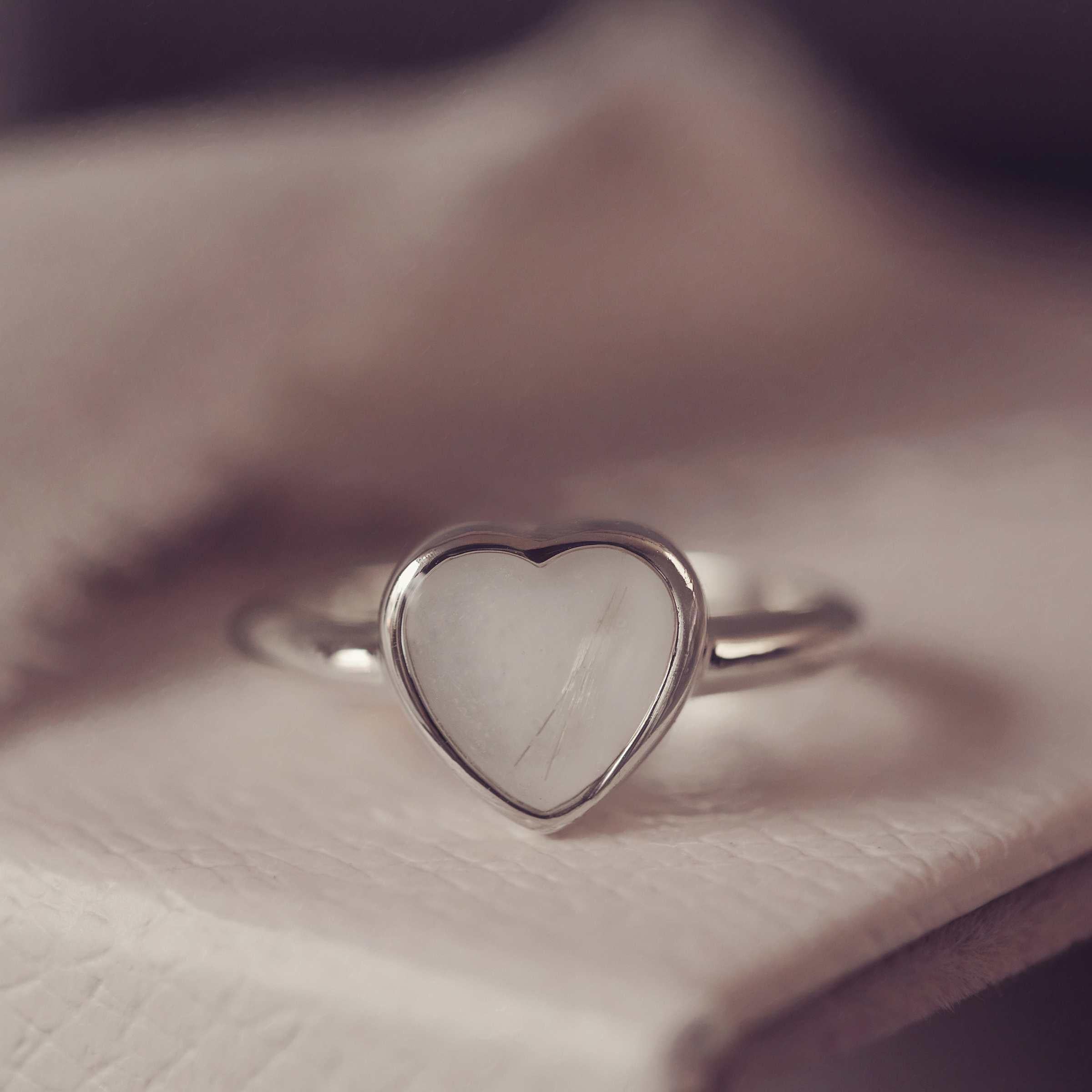 Heart-shaped silver ring on a textured surface