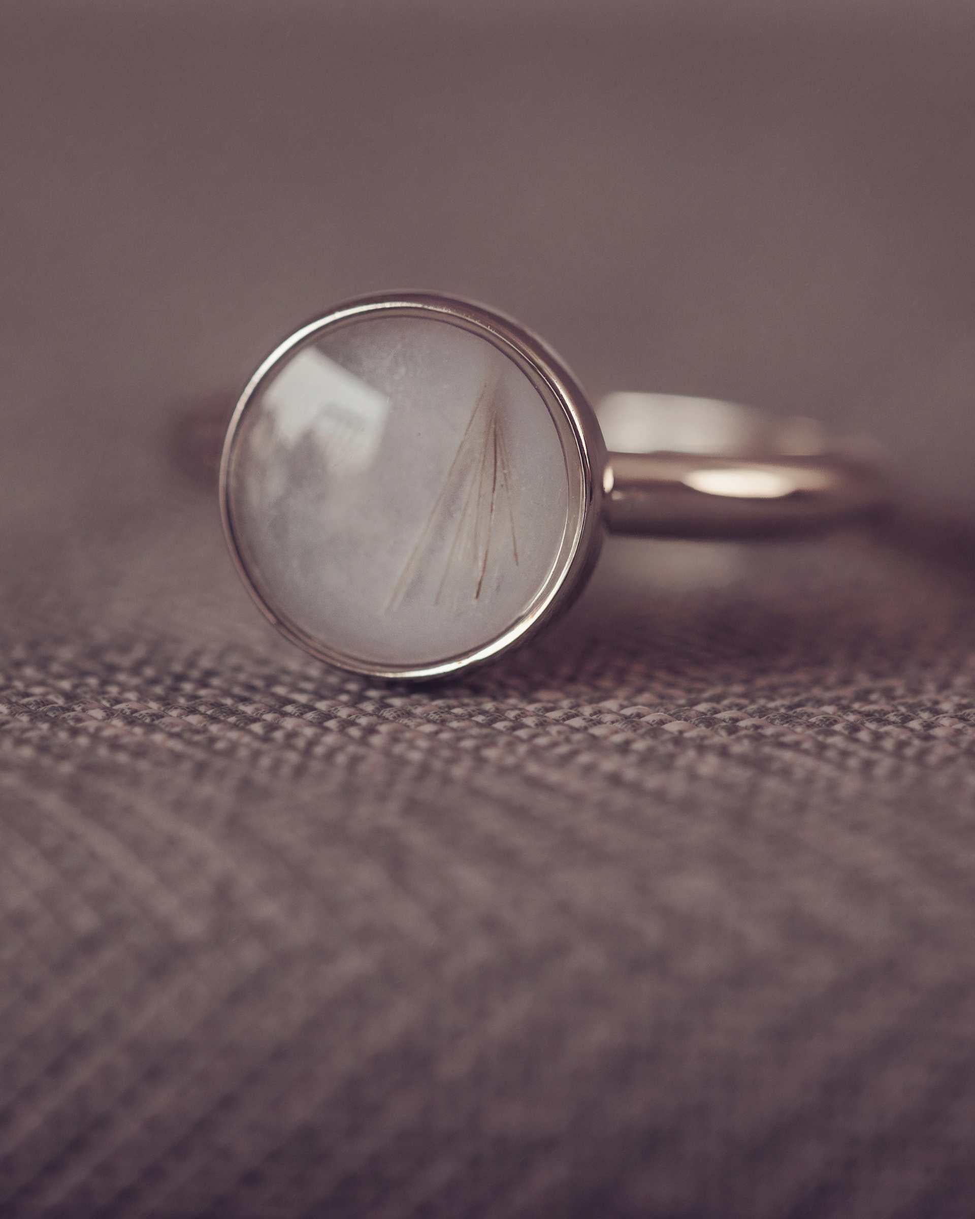 Silver ring with a circular ring on a textured brown surface